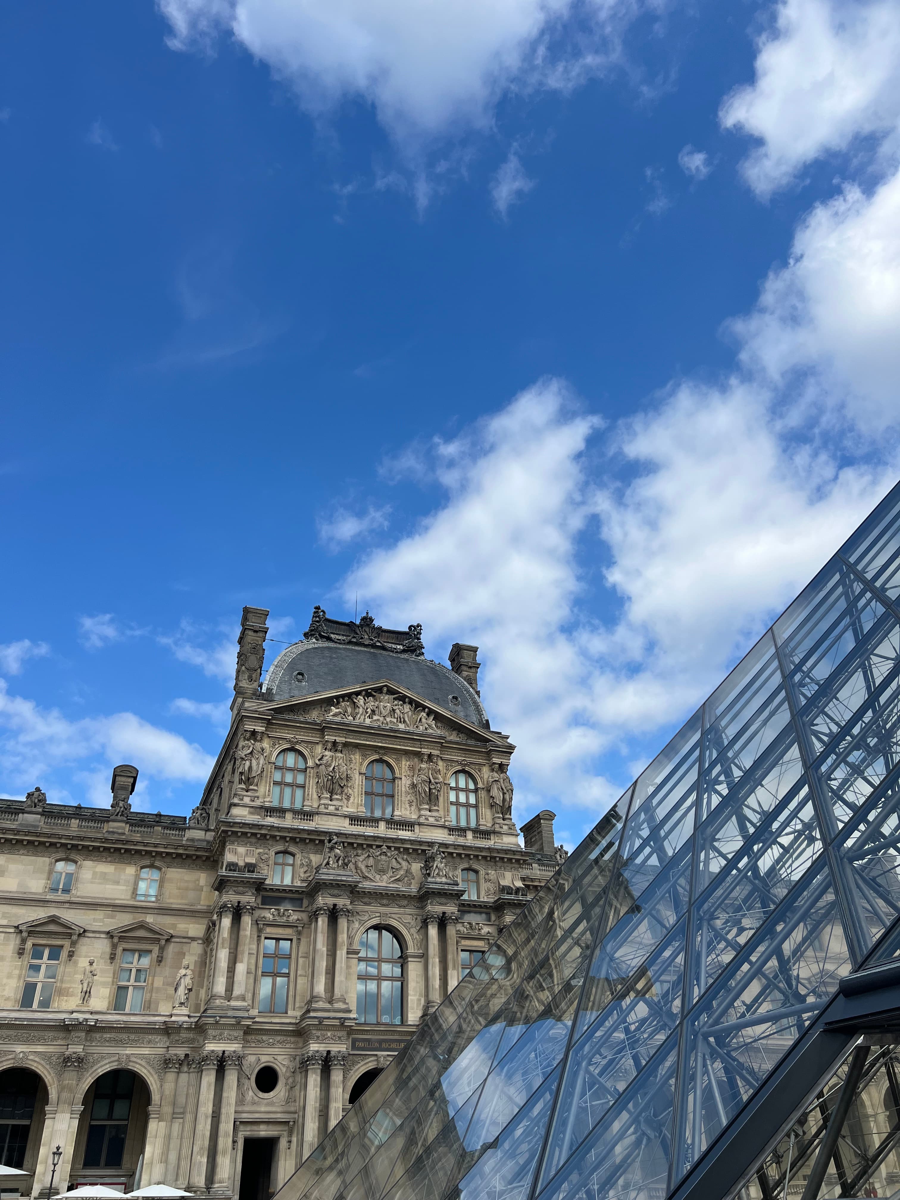 An upward angle of the Louvre on a sunny day with clouds