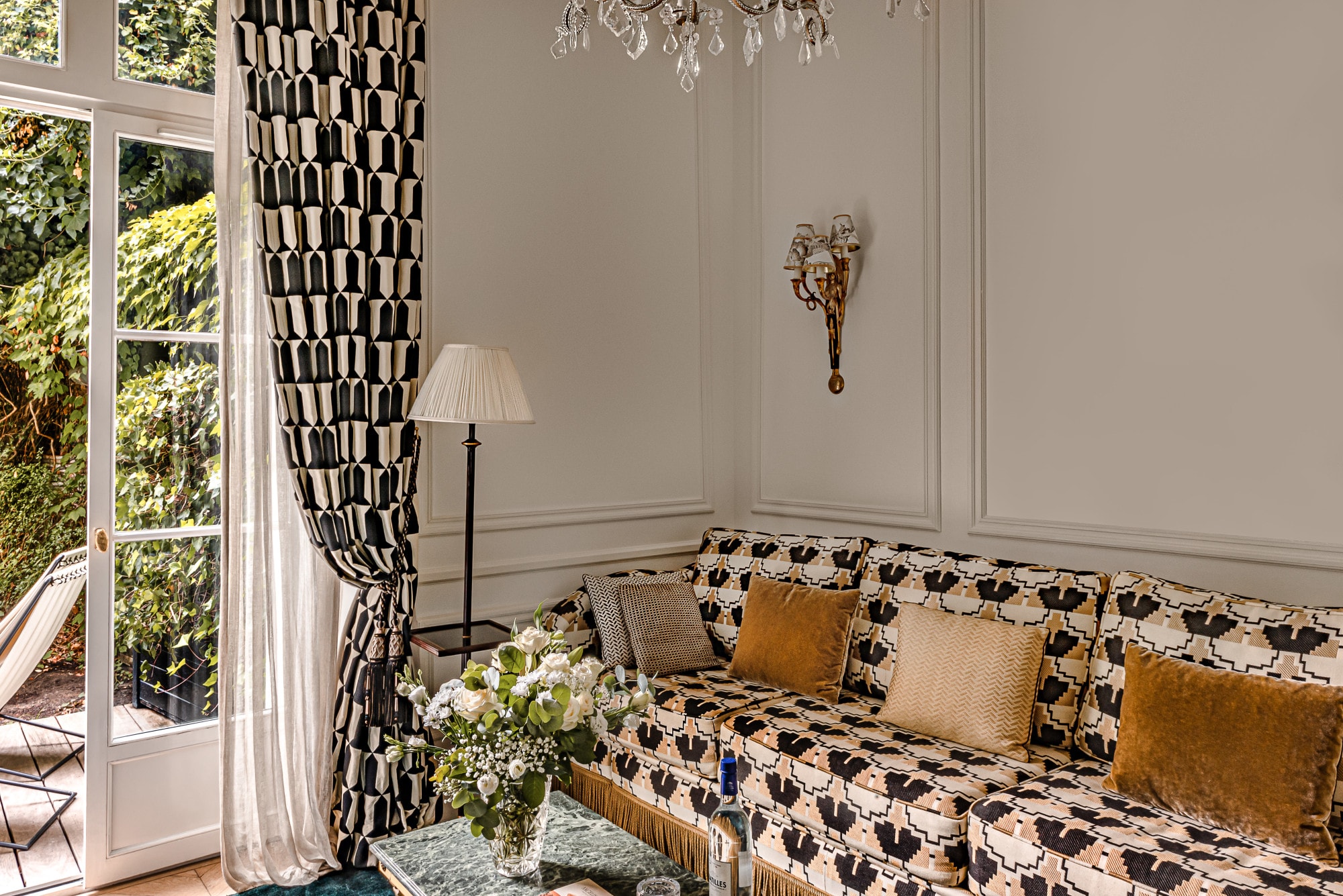 a brightly patterned couch near a draped floor-to-ceiling garden window