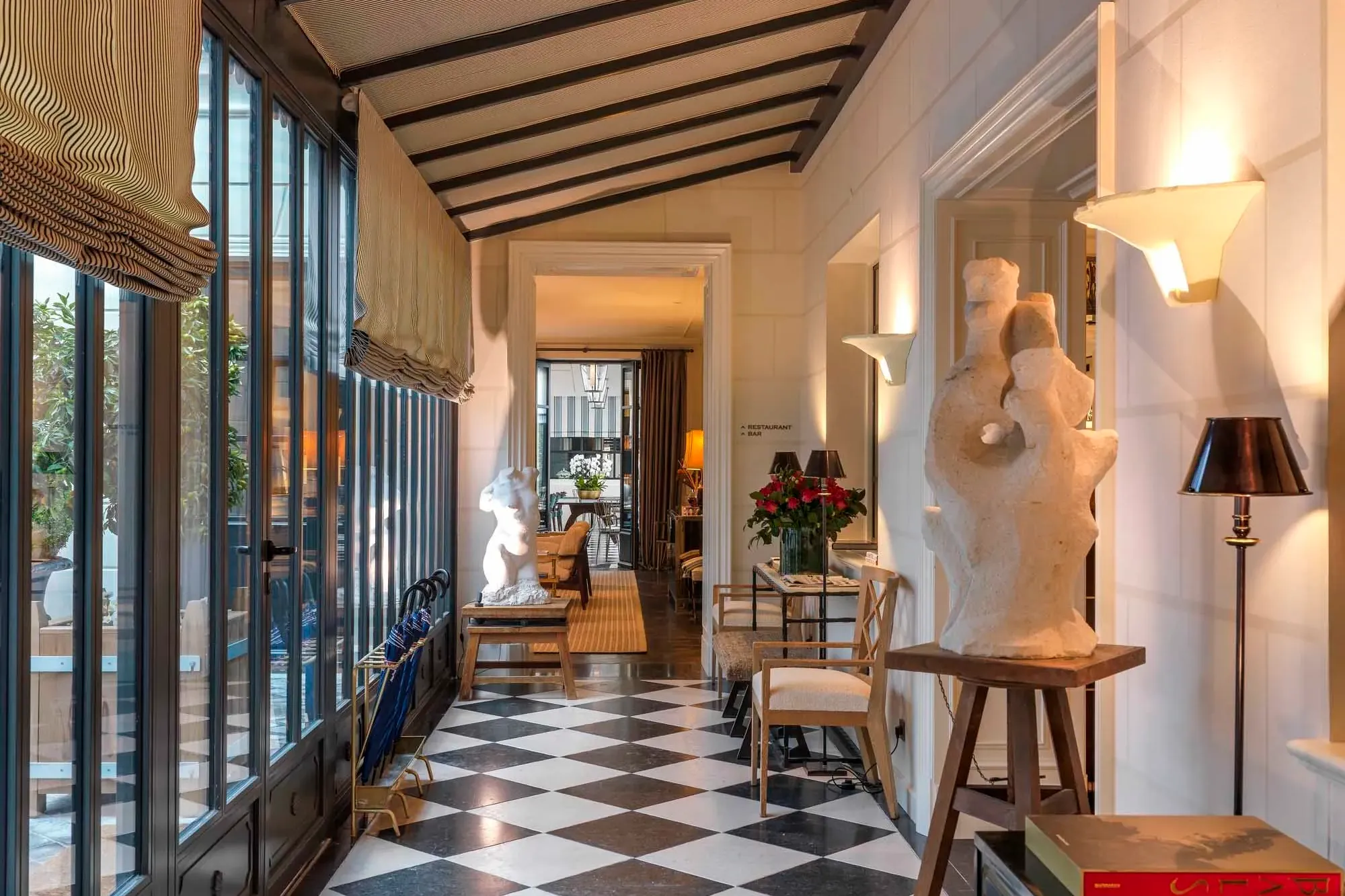 a walkway with black-and-white checkered floors and white statues