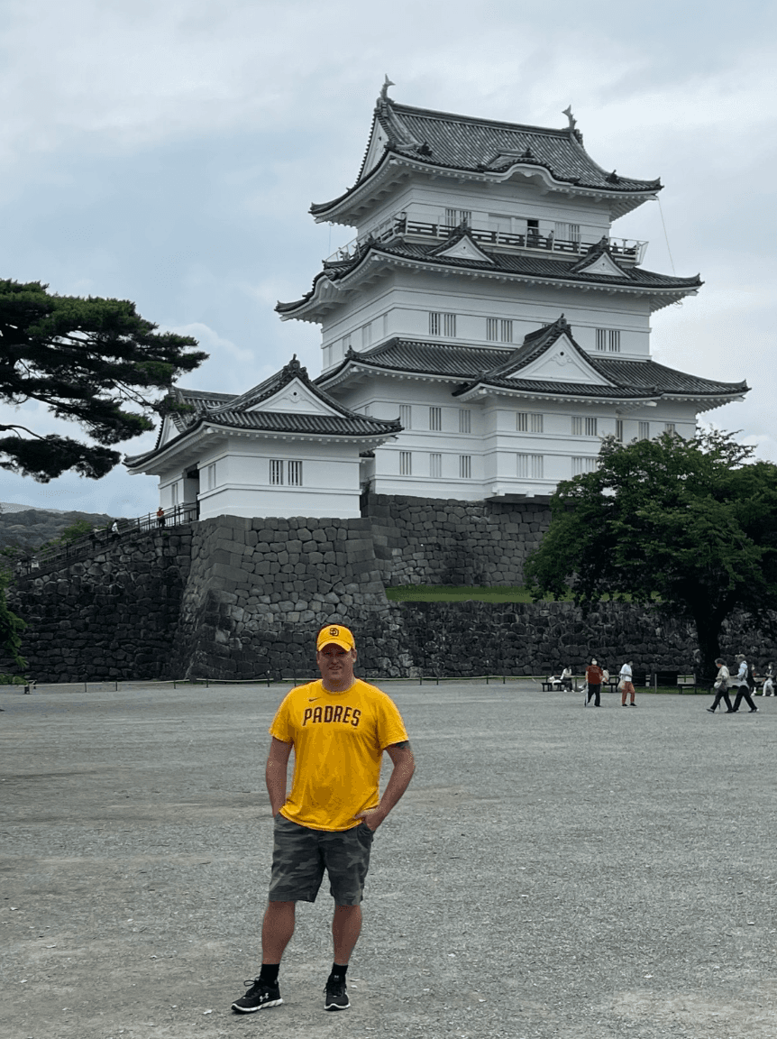 Michael wearing a yellow shirt and posing in front of a temple.