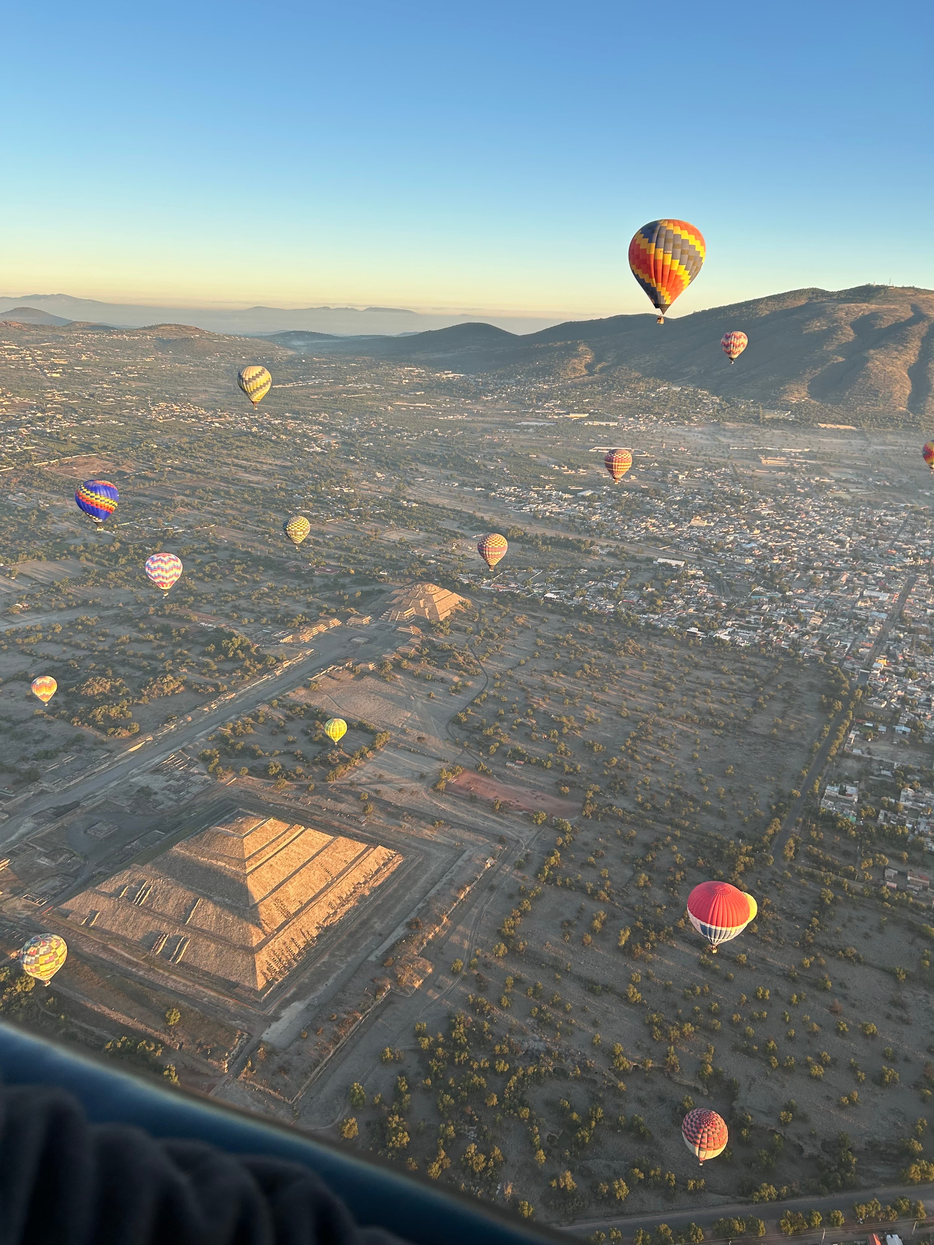 Aerial view of hot air balloons flying over pyramid