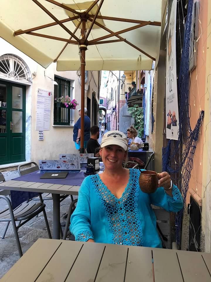 Travel advisor Shannon in a blue shirt and hat sitting at an outdoor cafe in a narrow street