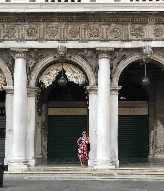 Travel advisor Shannon standing in a colorful dress under arches and pillars in St. Mark's Square plaza