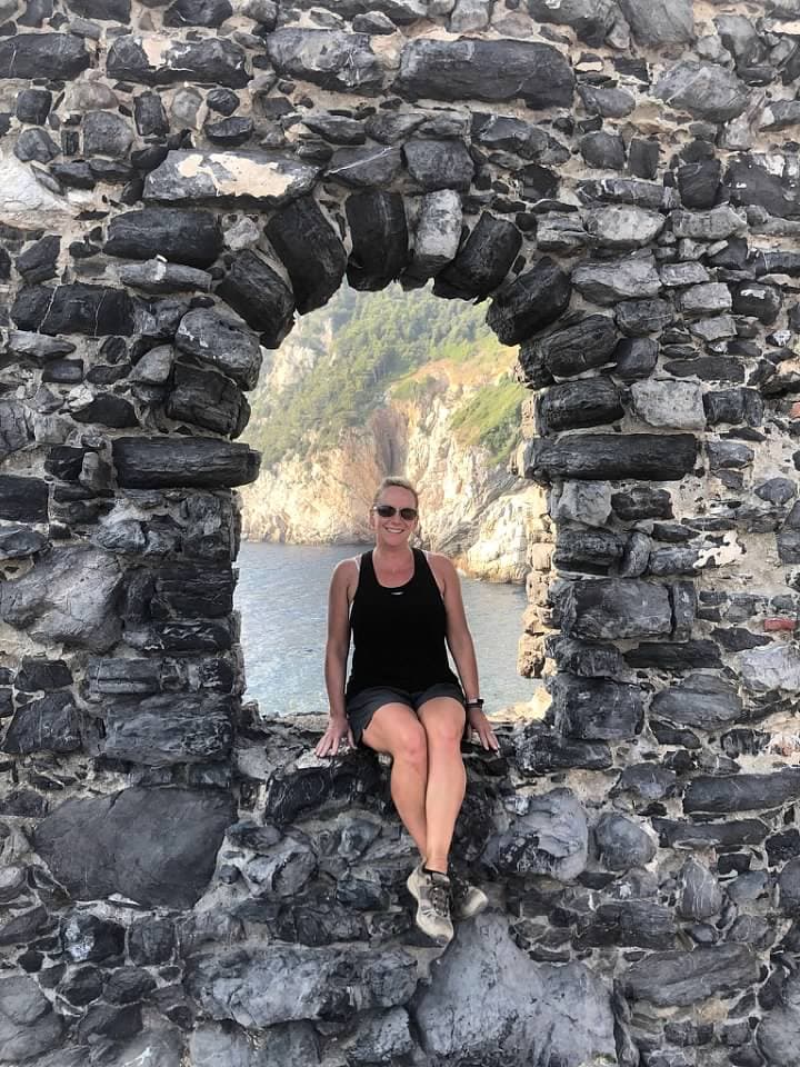Travel advisor Shannon sitting in the hole of a rocky wall with opening with ocean view