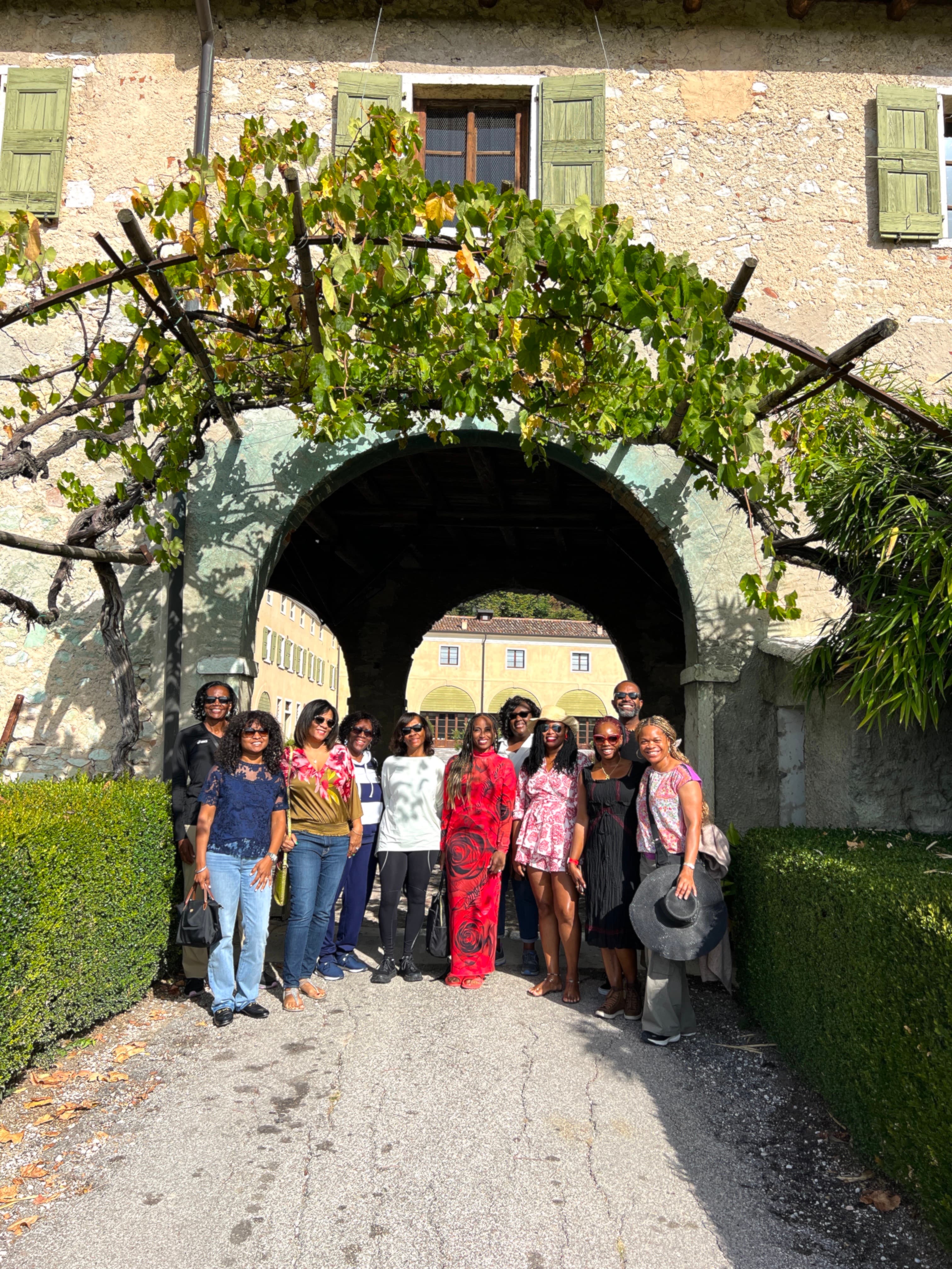 Nadeen and a group of travelers posing for a picture outside beneath a stone and vine covered archway.