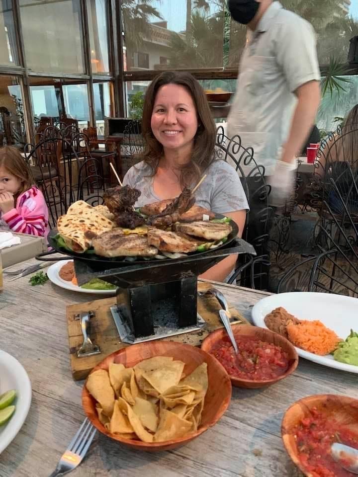 Travel advisor Tiffany sitting at a restaurant with a variety of dishes on the table