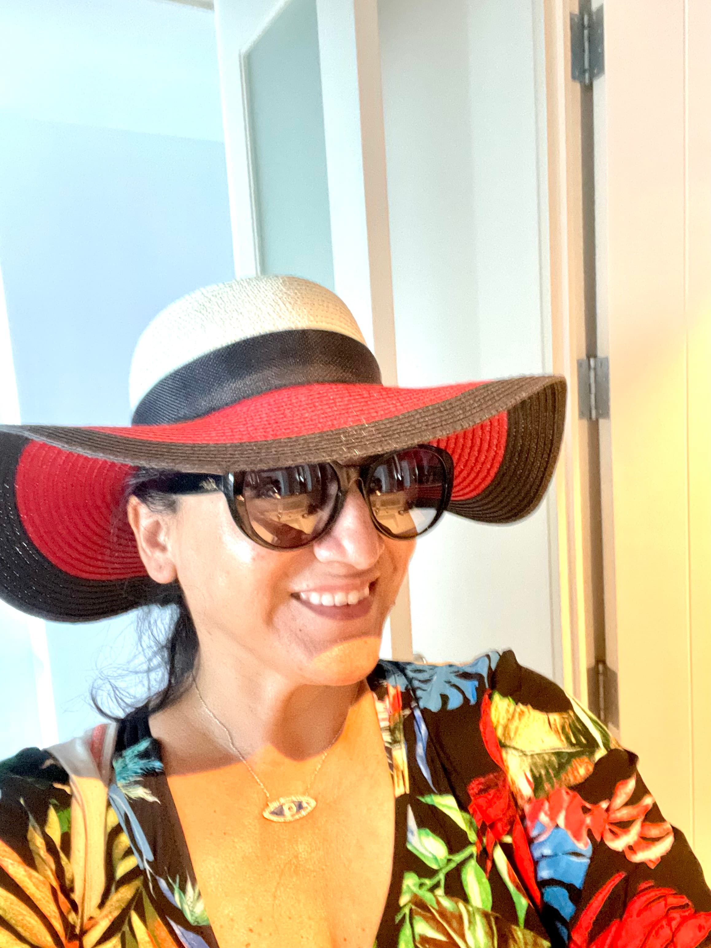 Travel advisor Lisa wearing colorful shirt and red, white and black hat and sunglasses