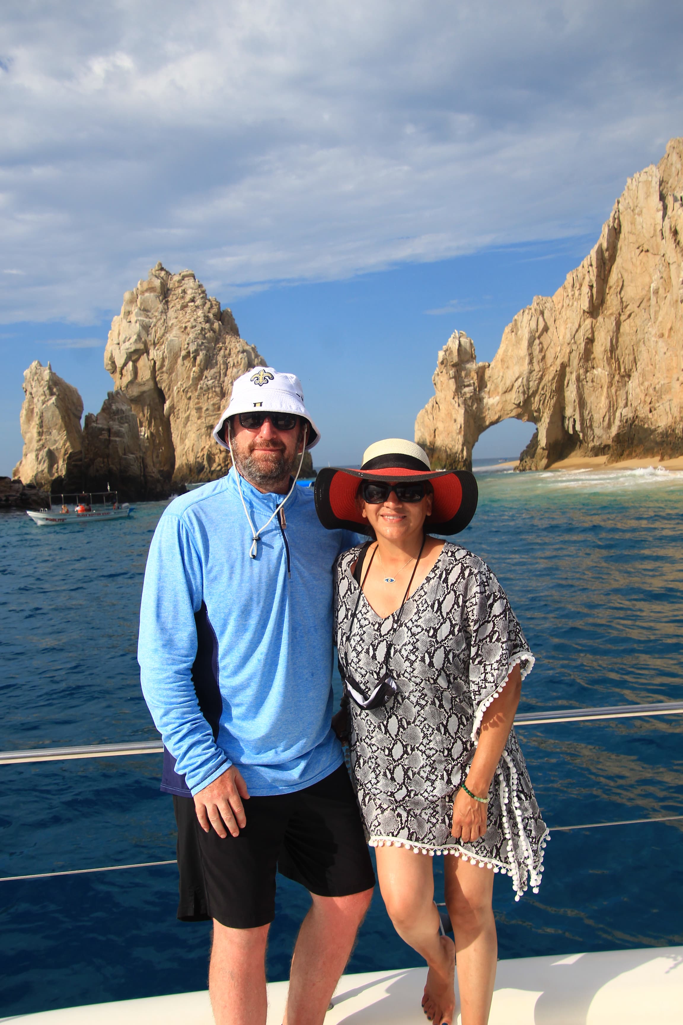 Travel advisor Lisa posing on the boat with husband in front of the Arch of Cabo San Lucas