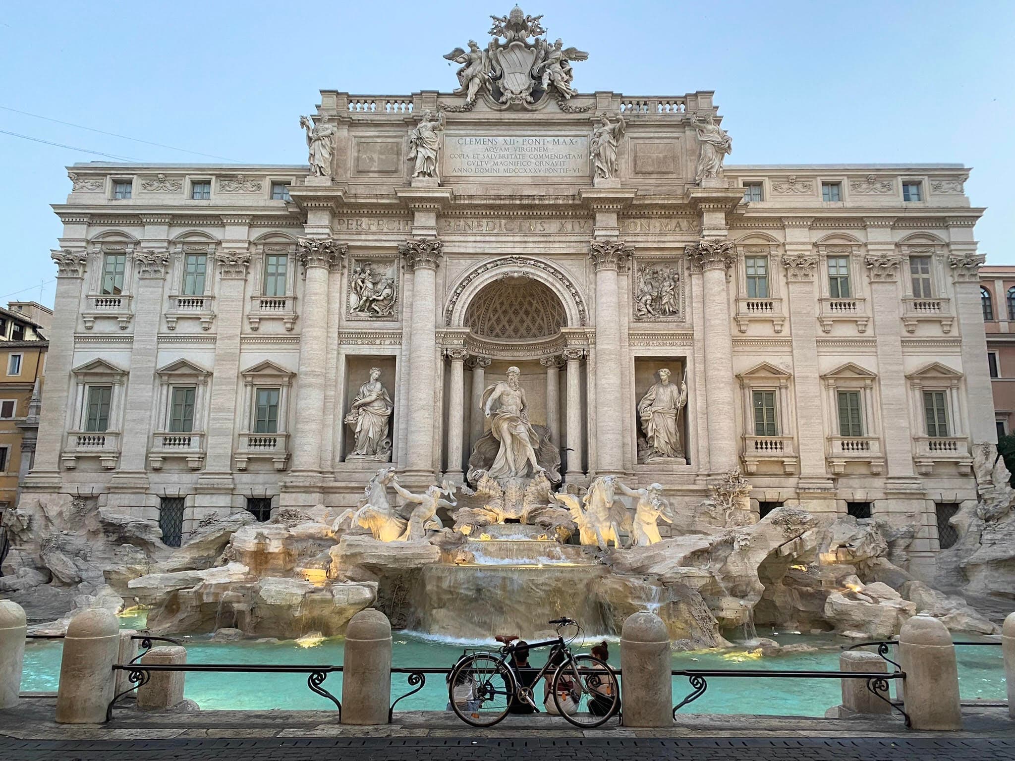 View of the Trevi Fountain in Rome with a bicycle leaning against the railing