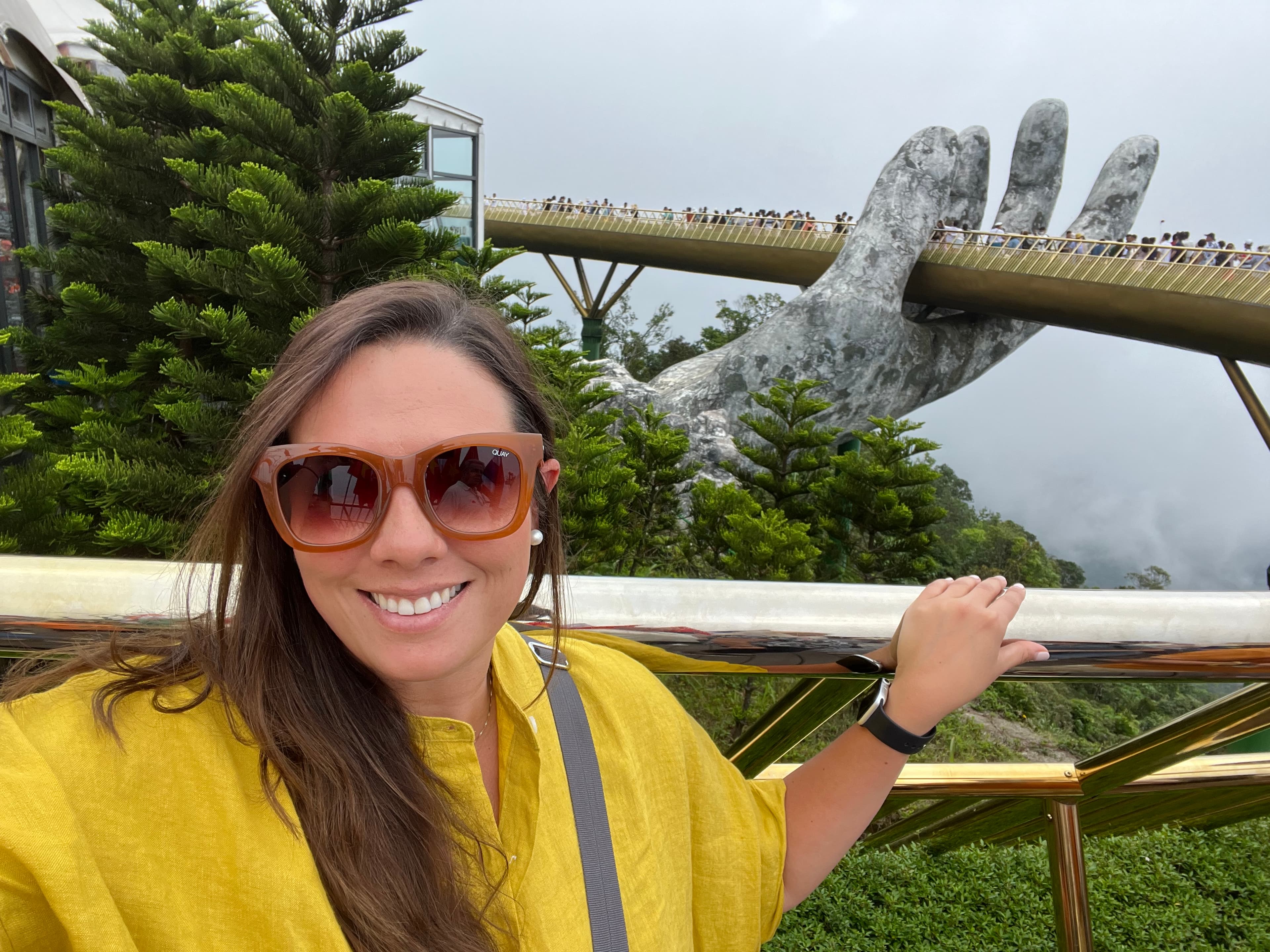 Travel advisor Andrea in a yellow shirt and sunglasses standing in front of the Golden Bridge Vietnam
