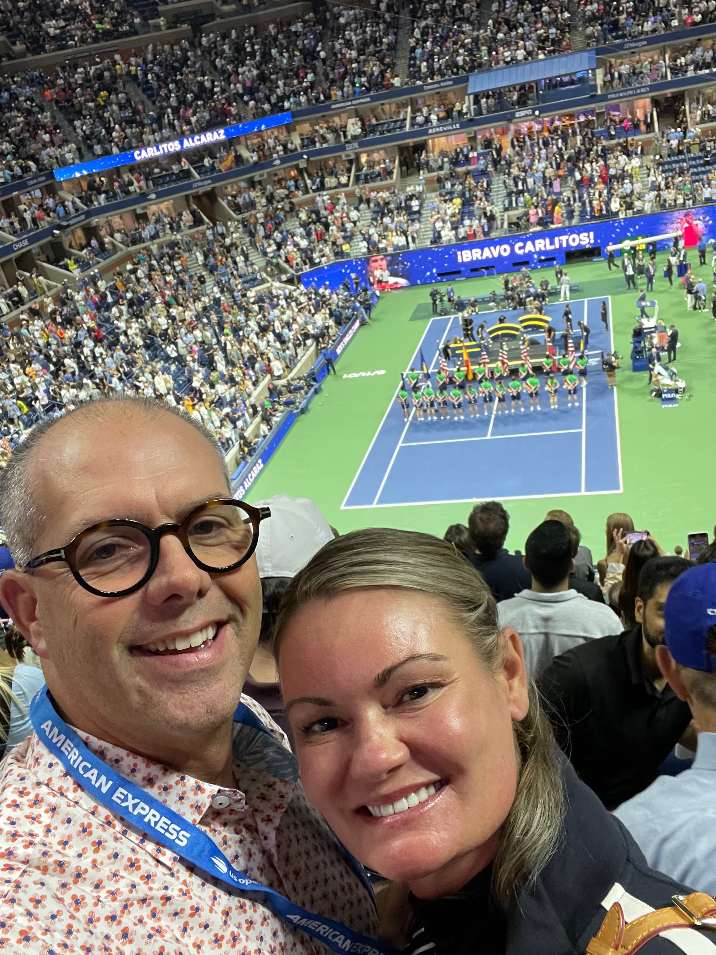 Elizabeth taking a selfie with a man in a tennis stadium