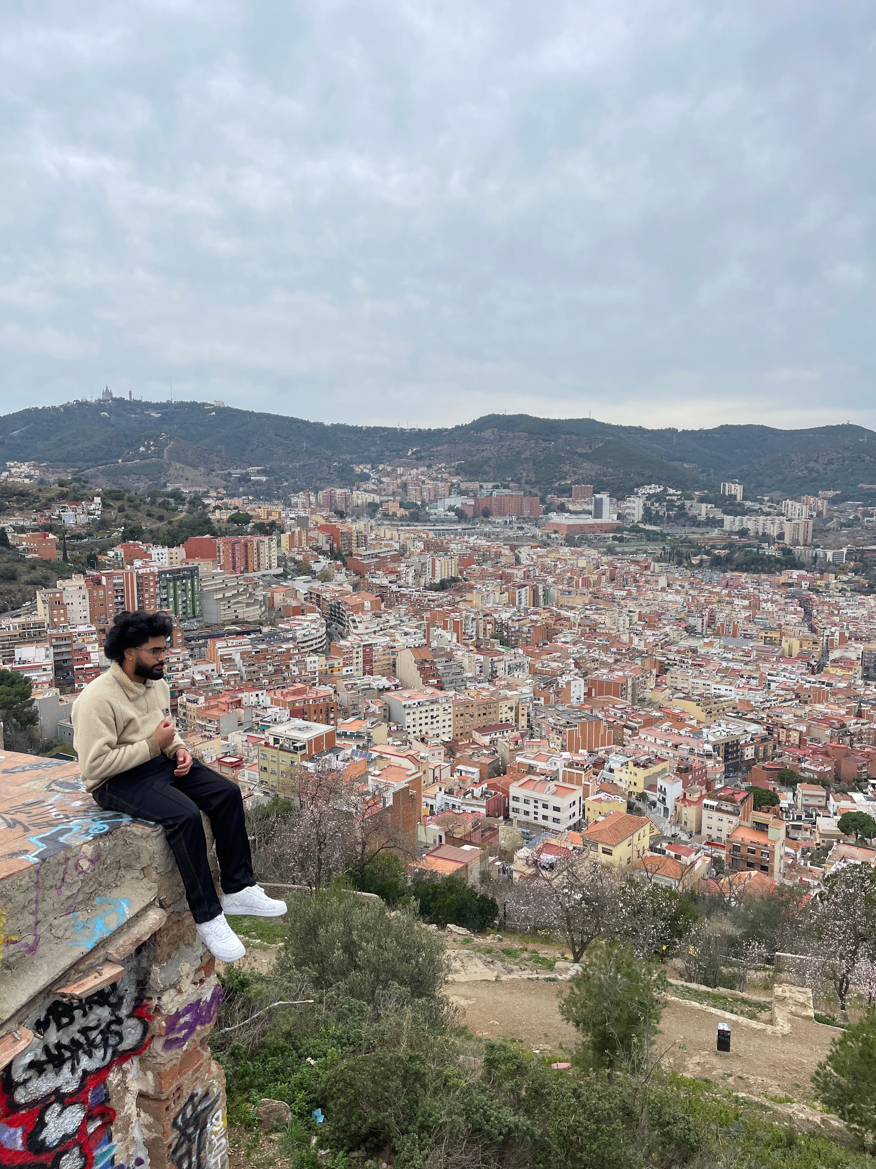ravel advisor Matthew sitting on the edge of a high wall overlooking a large city