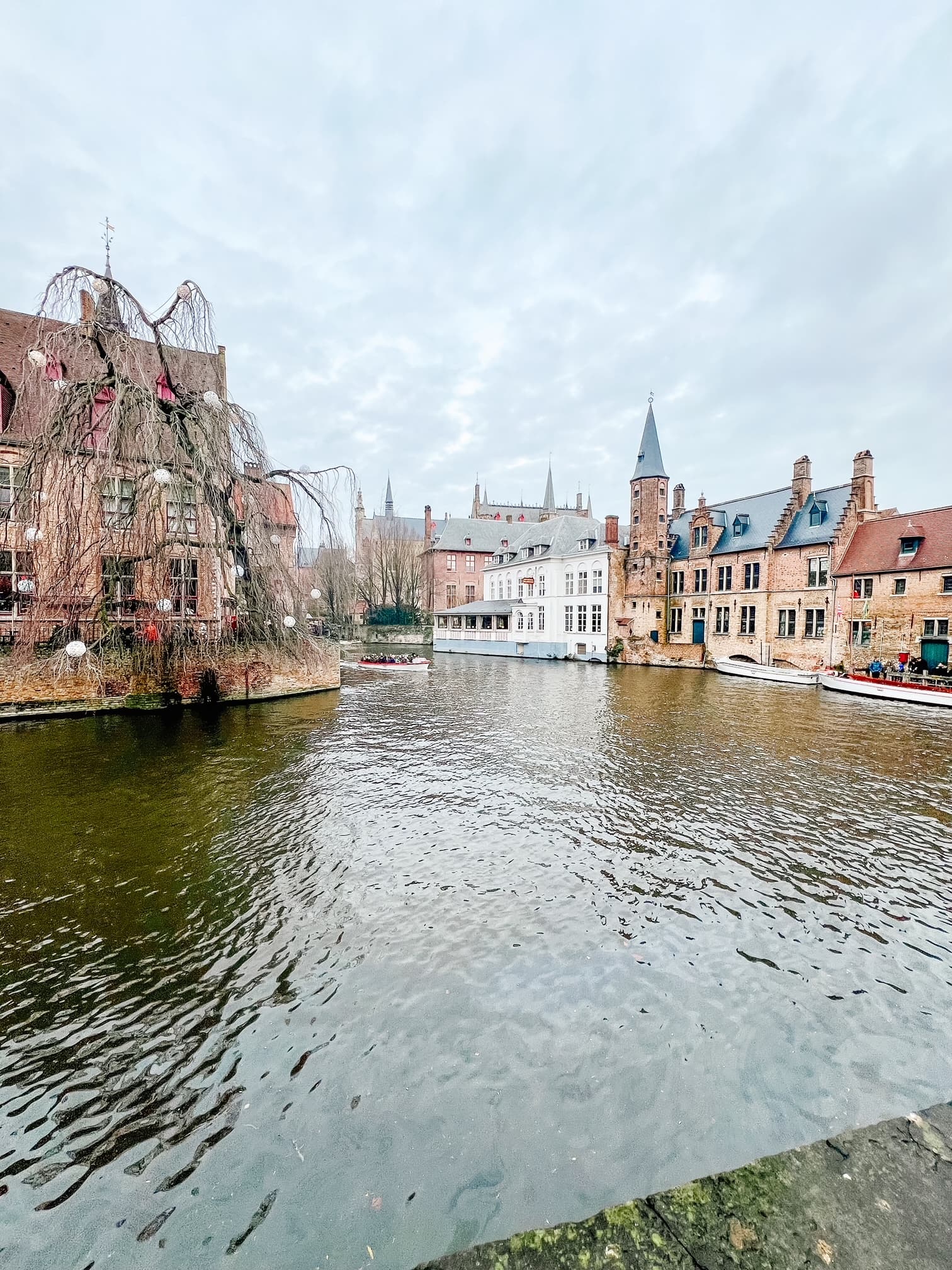 A view of a river in a city with boats and old buildings on a cloudy day