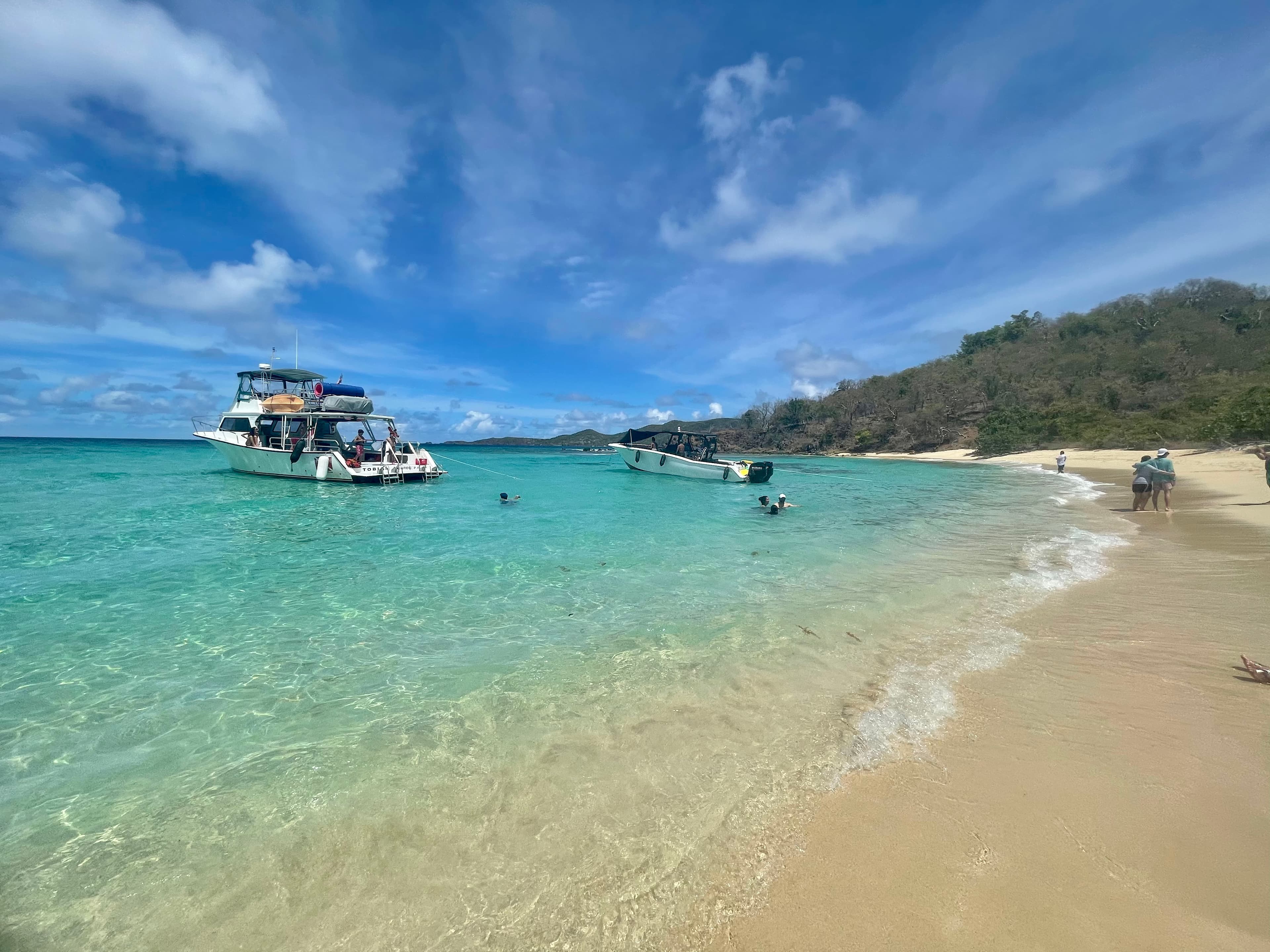 Beautiful view of beach with a boat in view and people swimming