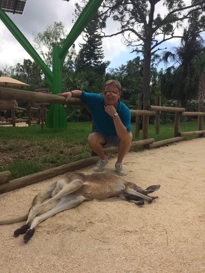 Barry squatting down to pose next to a sleeping kangaroo.