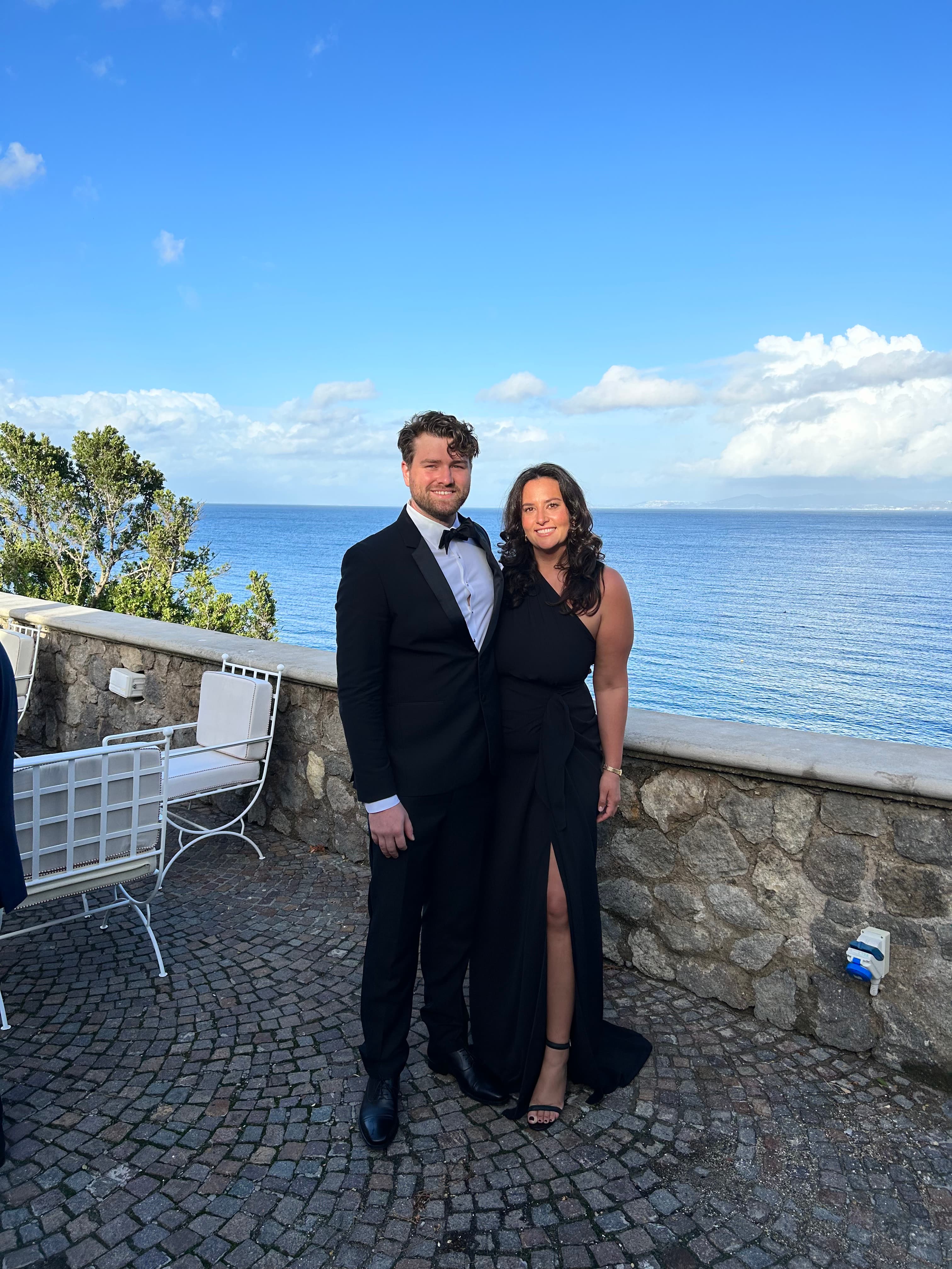Travel advisor Rebecca King posing in an elegant black dress with companion overlooking the ocean