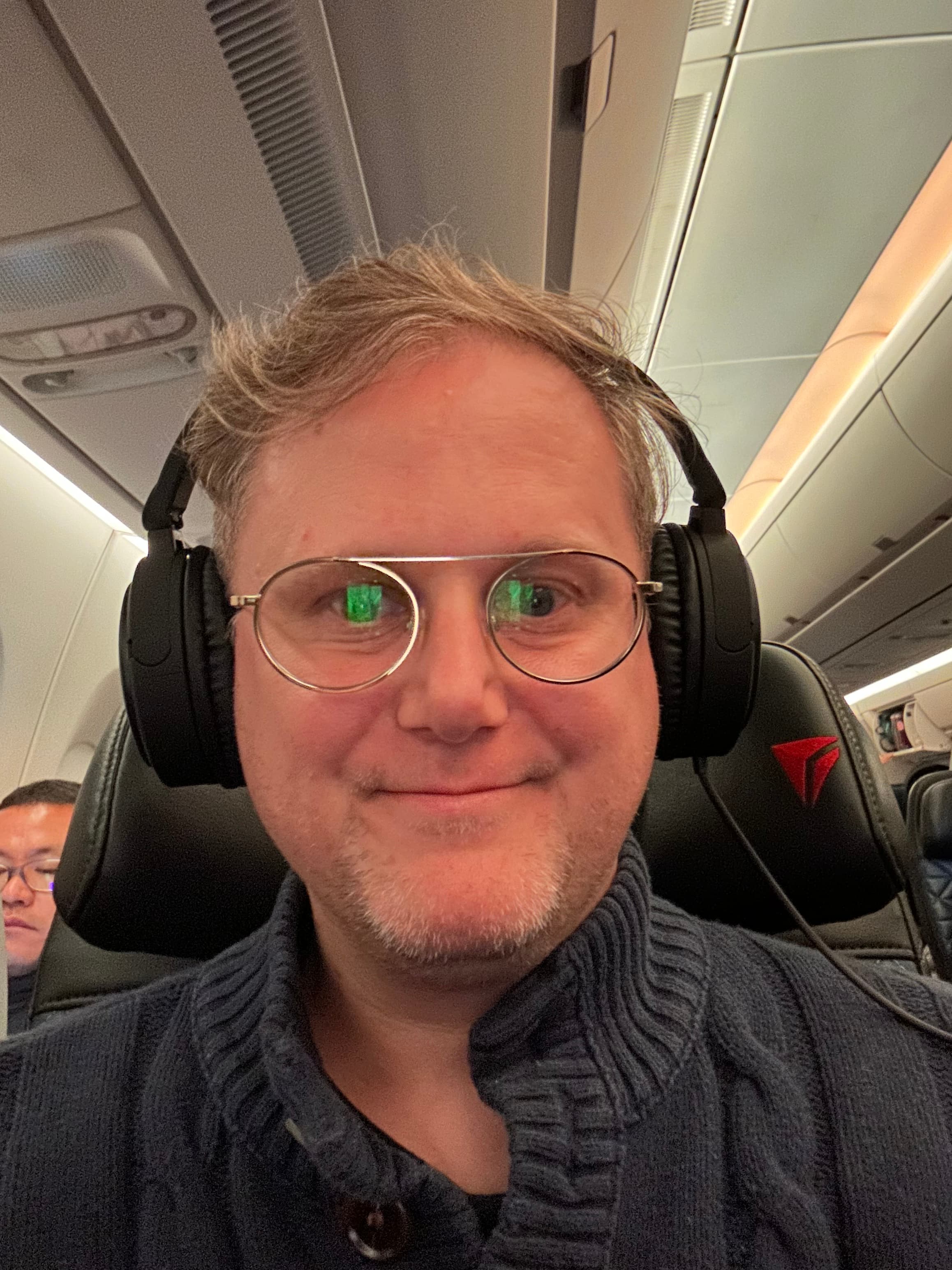 Travel advisor Joshua sitting on a plane wearing headphones