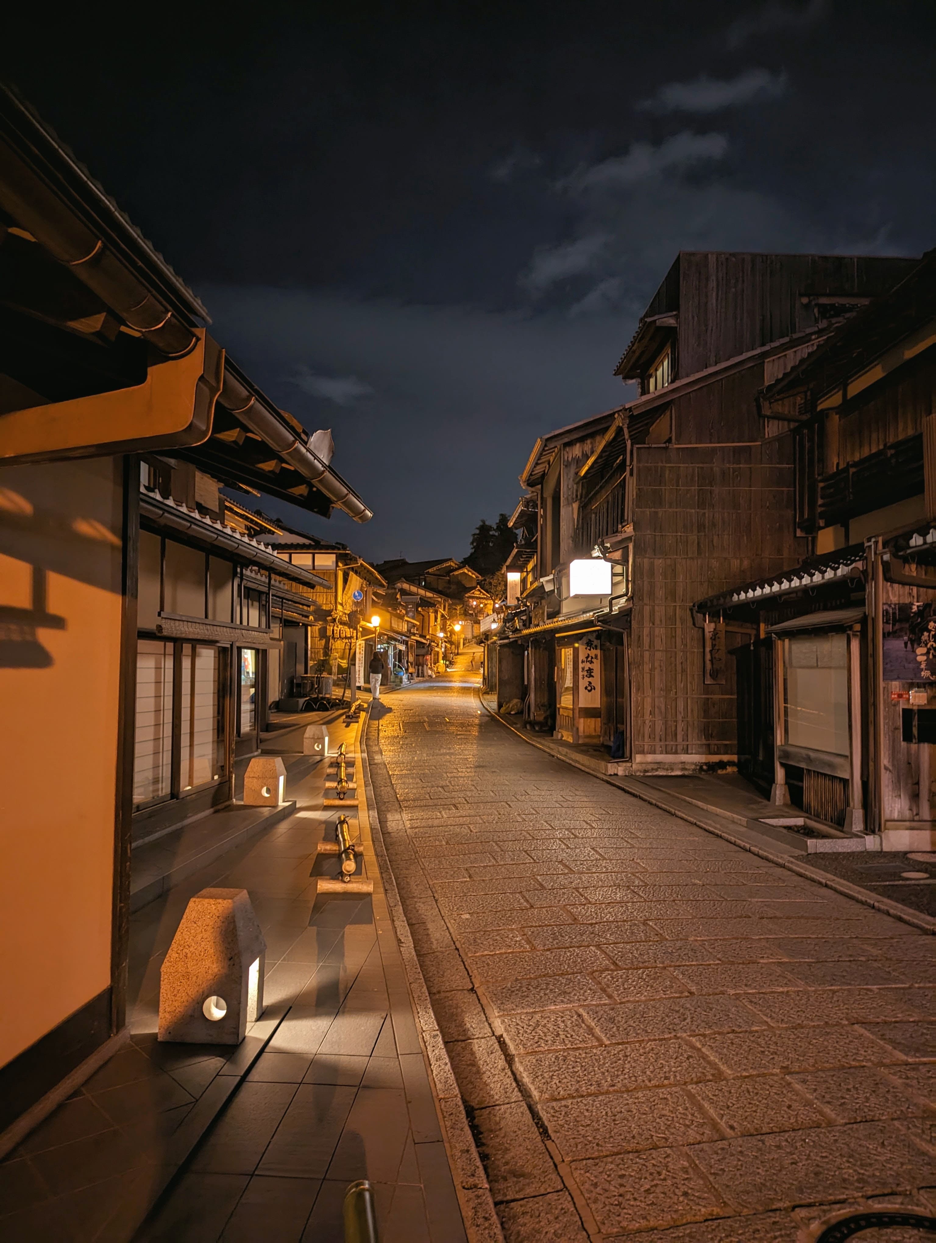 A city street at nighttime. There are lights on the buildings.