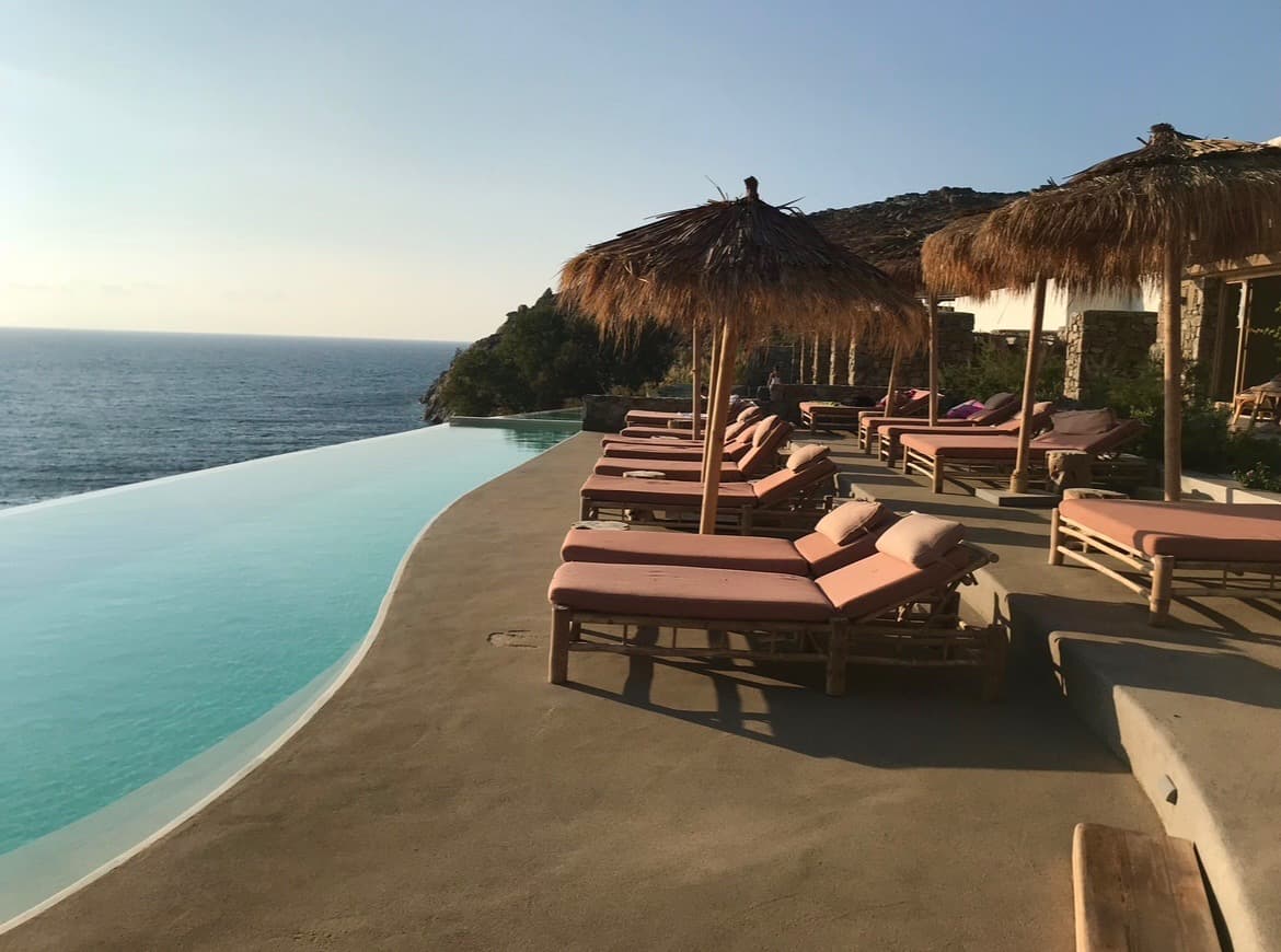 Beautiful view of an infinity pool and sun loungers with pink cushions