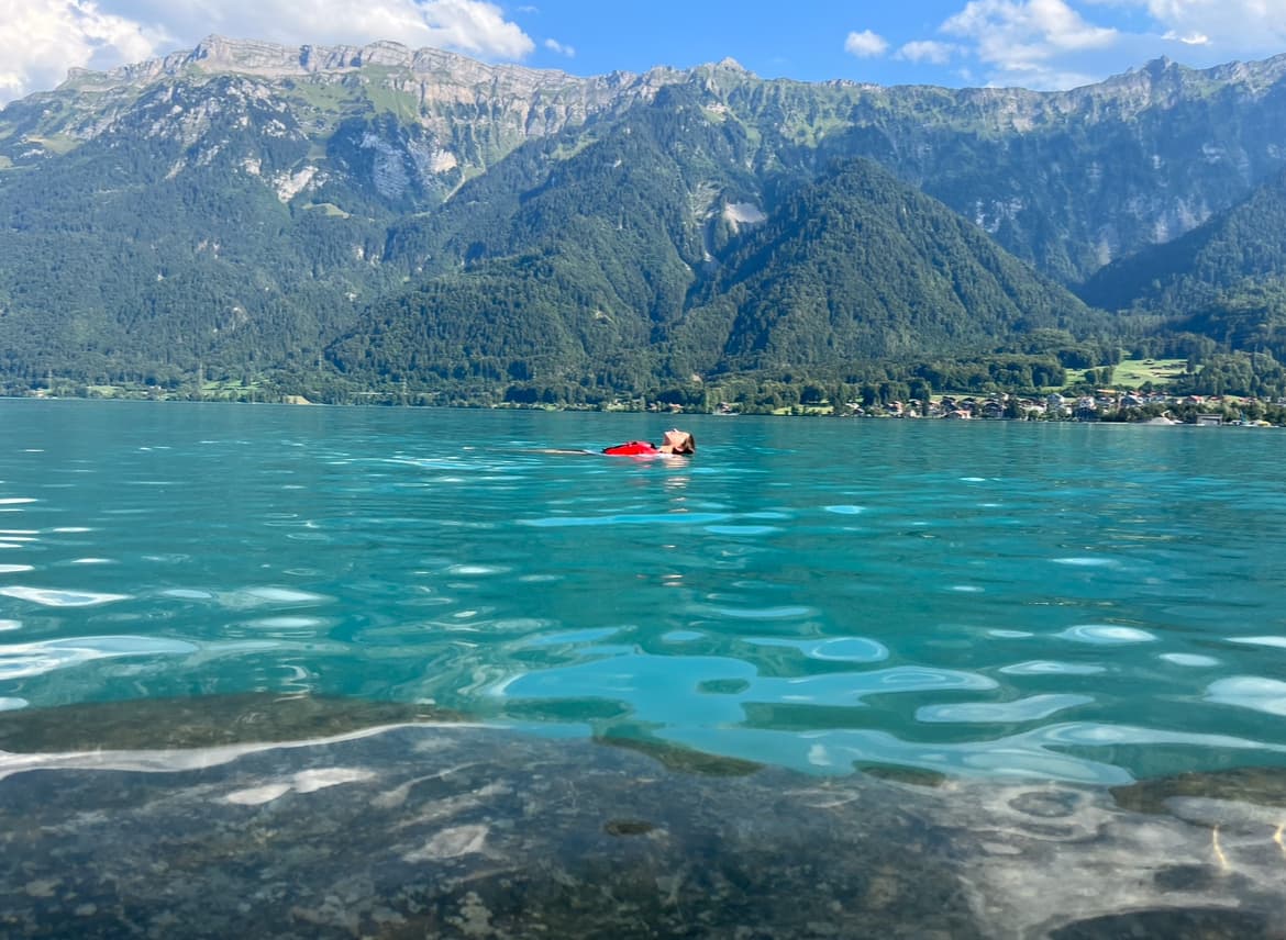 Travel advisor Kayla floating in a turquoise lake with mountains in view
