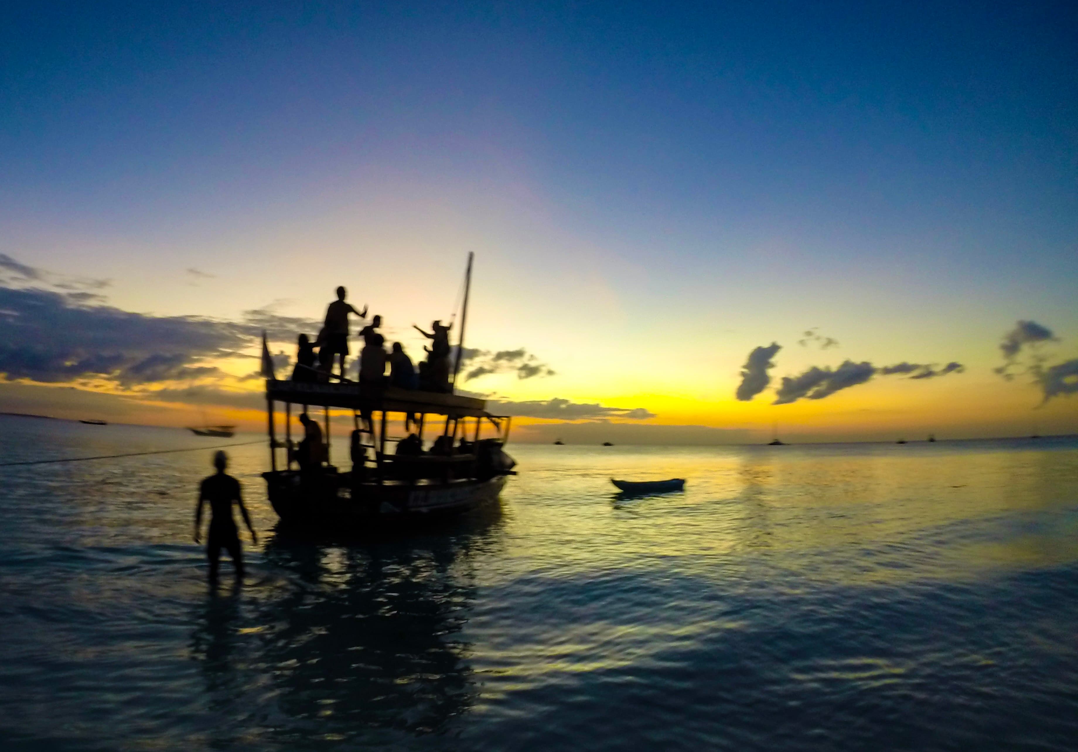 View of a small two-level boat carrying people at sunset