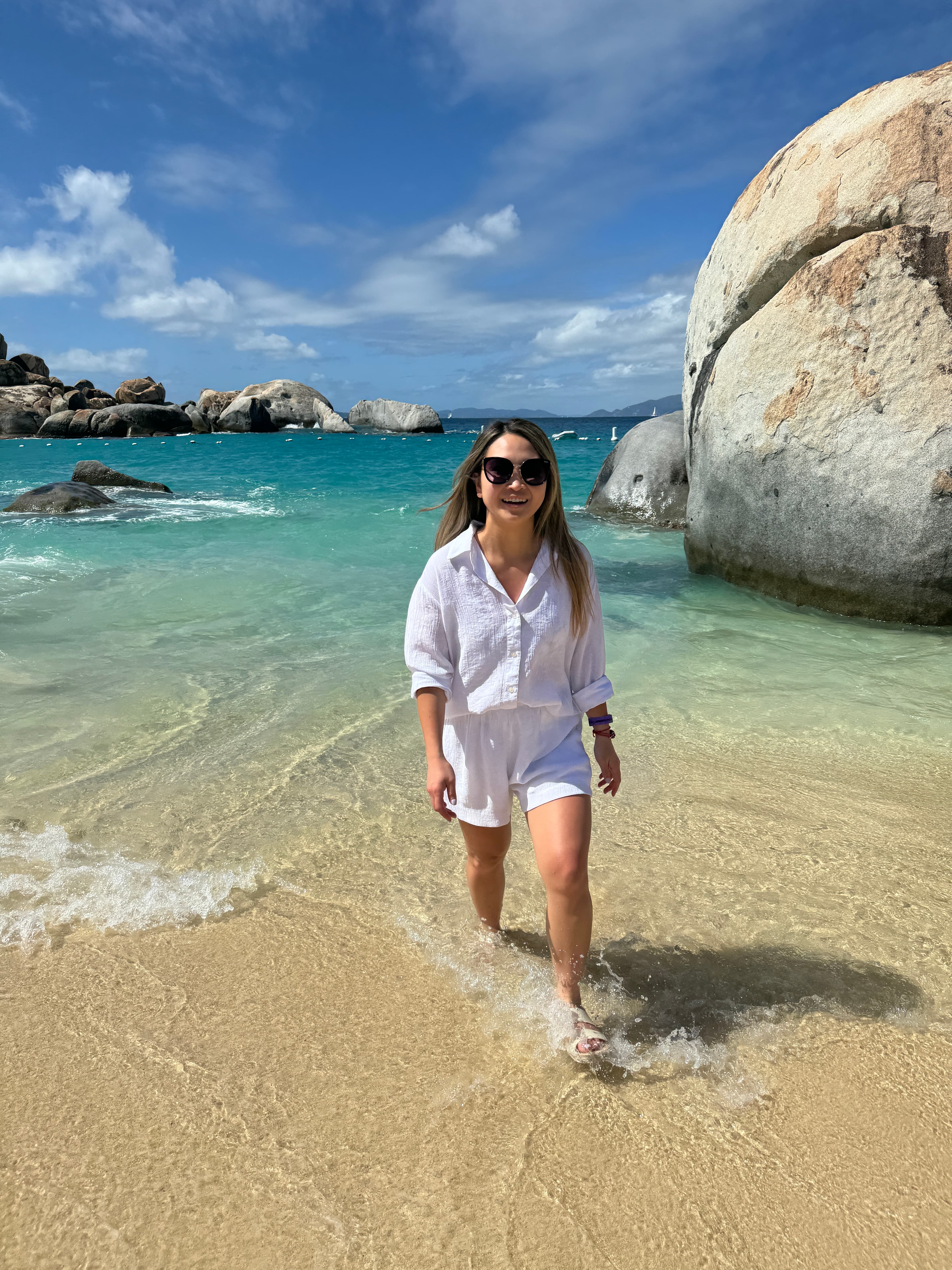 Travel advisor Truc posing for a picture in white outfit and sunglasses on the beach