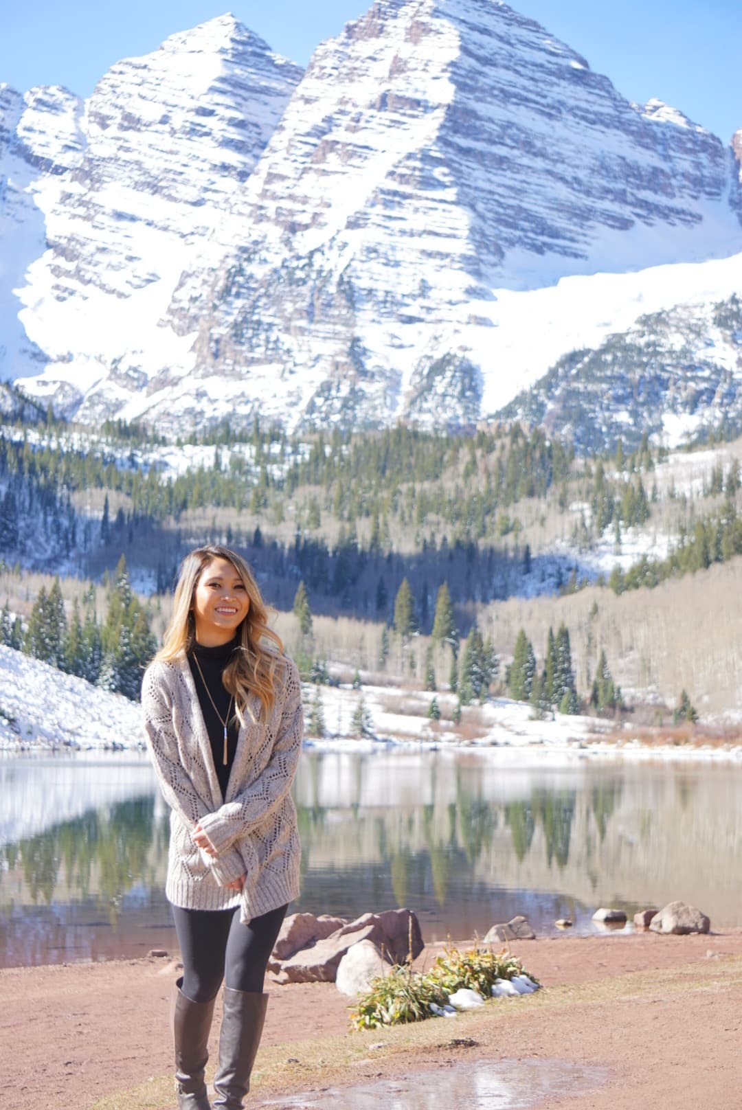 Travel advisor Truc posing for a photo in front of lake and snow.-capped mountains