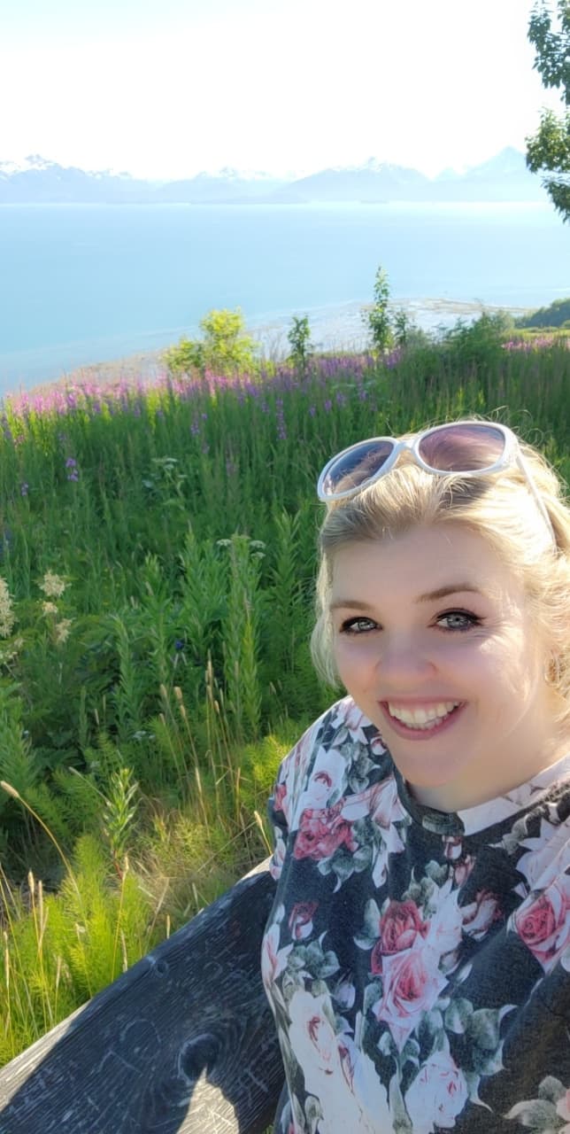 Travel advisor Erin posing for a selfie in front of beautiful view of purple flowers