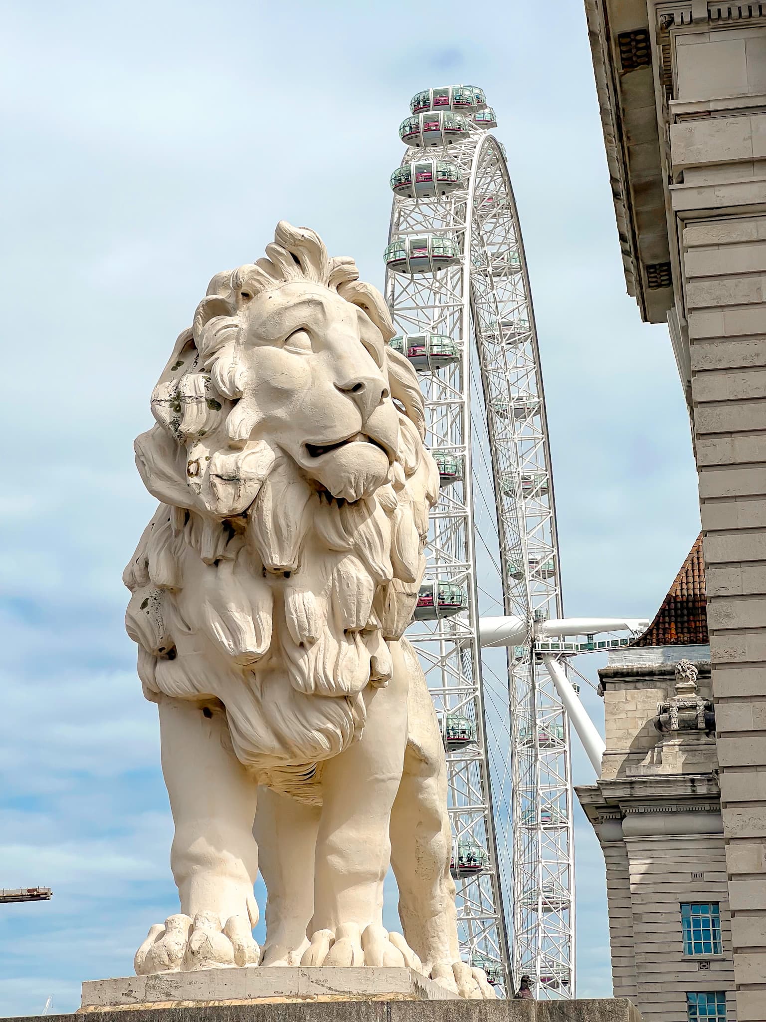View of a lion sculpture with large ferris wheel behind