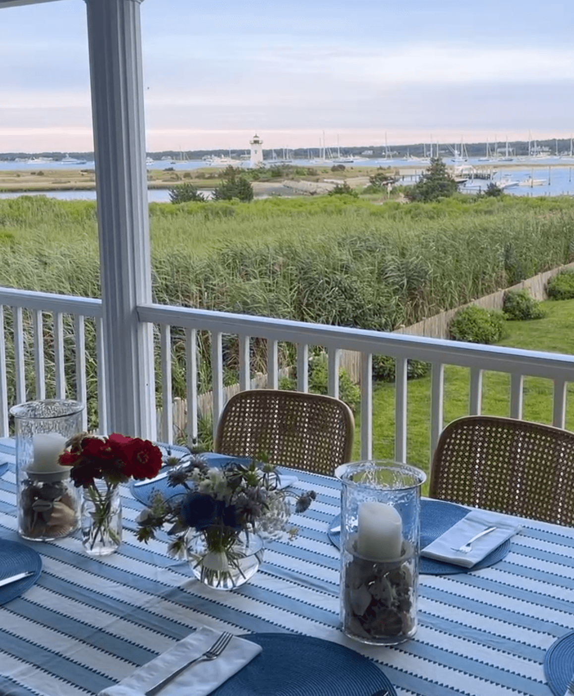 Beautiful dining setup of a hotel with white and blue striped tablecloth overlooking green gardens and water