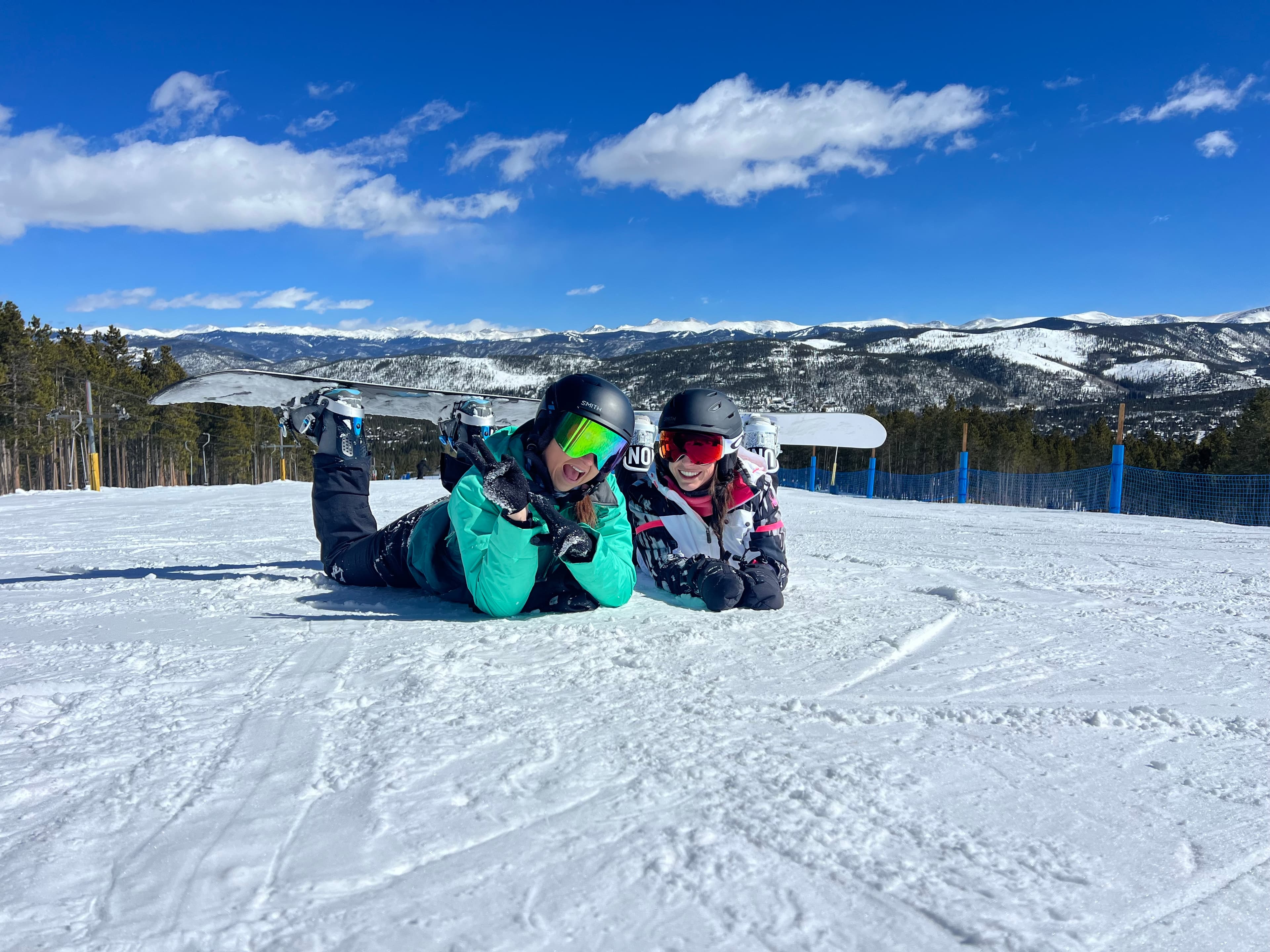 Travel advisor Sarah lying down in ski suit on ski slope with companion