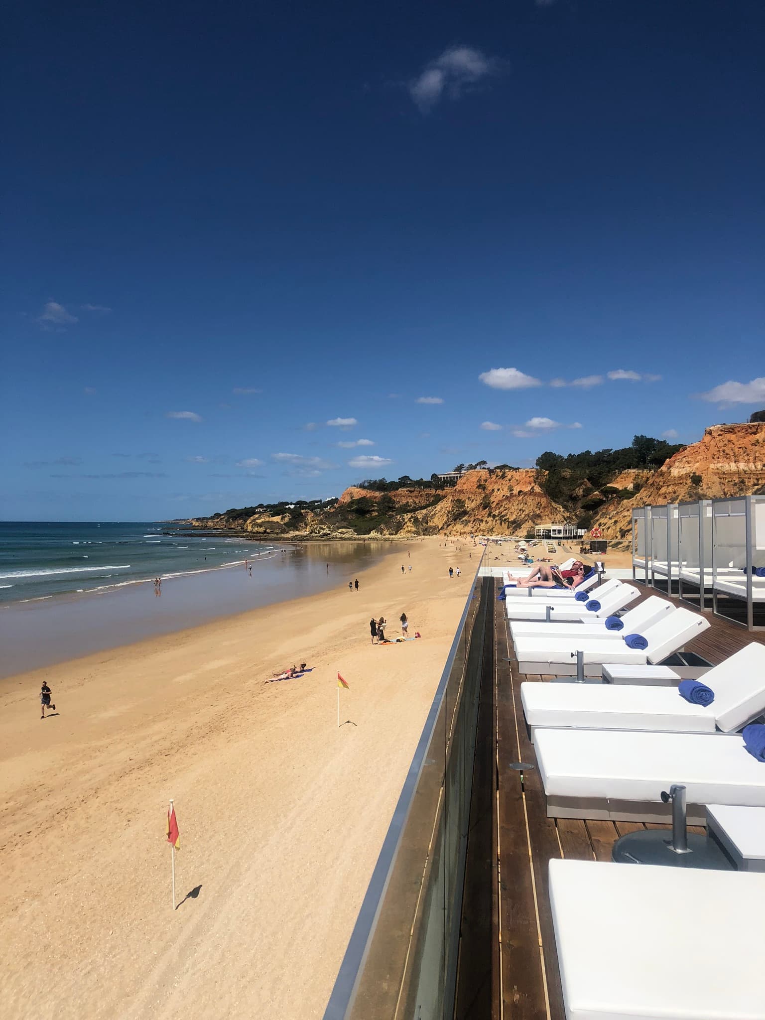 View of a beautiful beach and white sun loungers on a deck