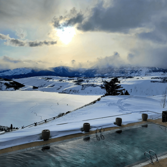 An infinity pool overlooking a snowy valley on an overcast day.
