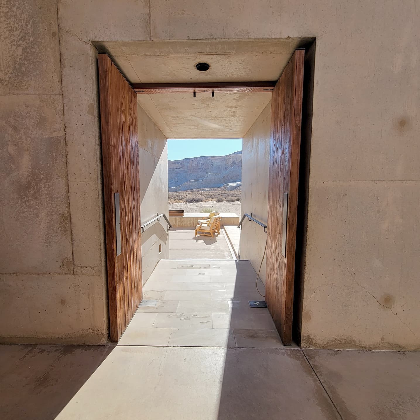 A view through a large wooden doorway of a patio with hills beyond.