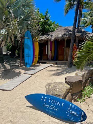 View of surfboards and a thatched hut on the beach