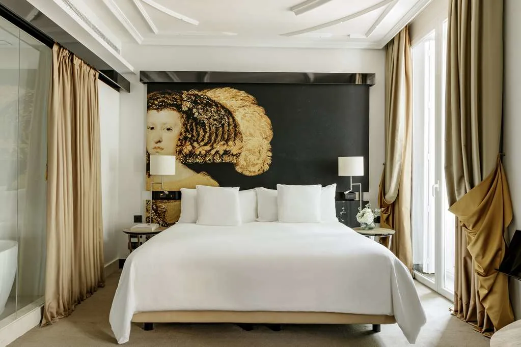 a white bed in front of a large headboard depicting a woman's head on a black background