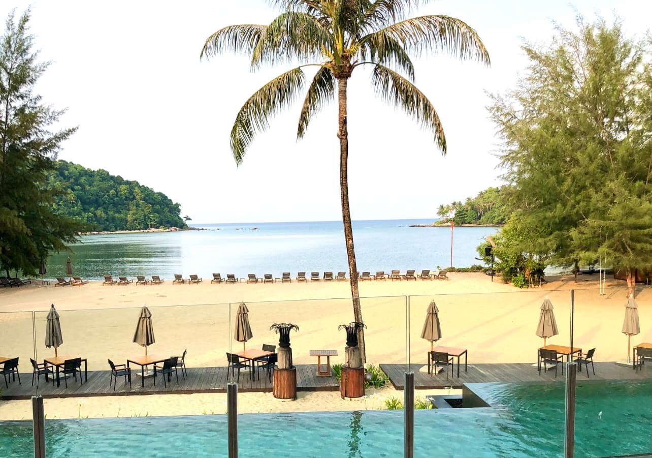A beautiful view of a beach with seating and palm trees.