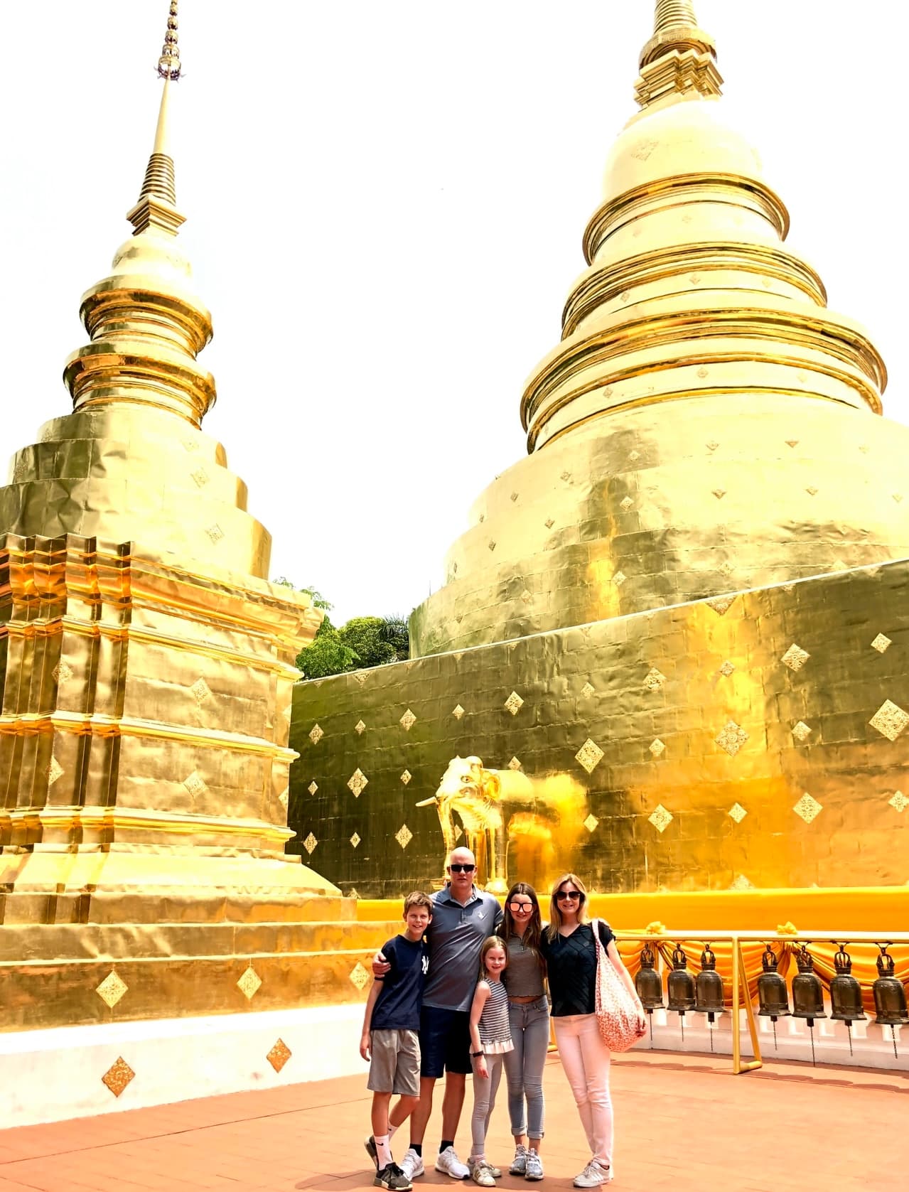 Ashley and her family posing for a photo with golden buildings in the distance.