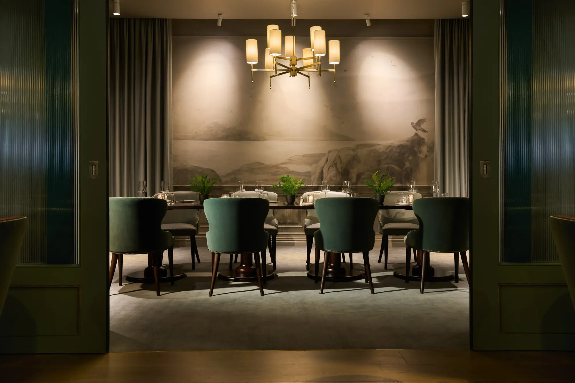 a long dining table surrounded by green chairs in a dimly lit room