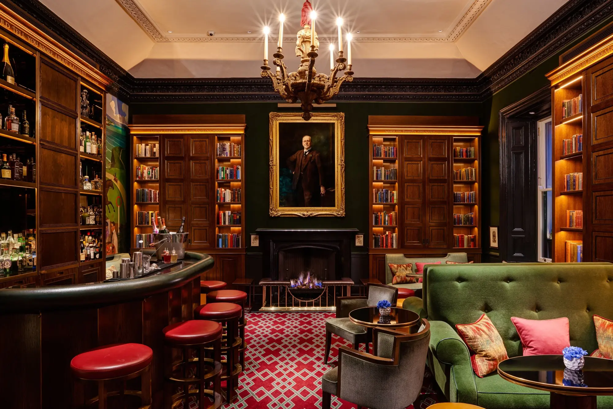 a handsome dimly lit library with a green couch and red carpet