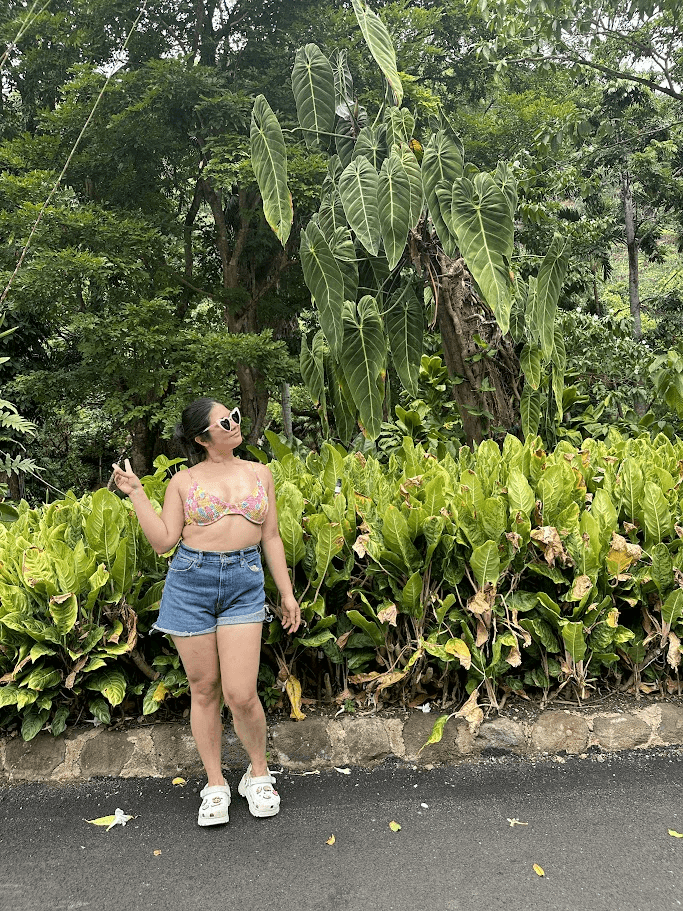 Claudine posing with a lot of green foliage in the background.