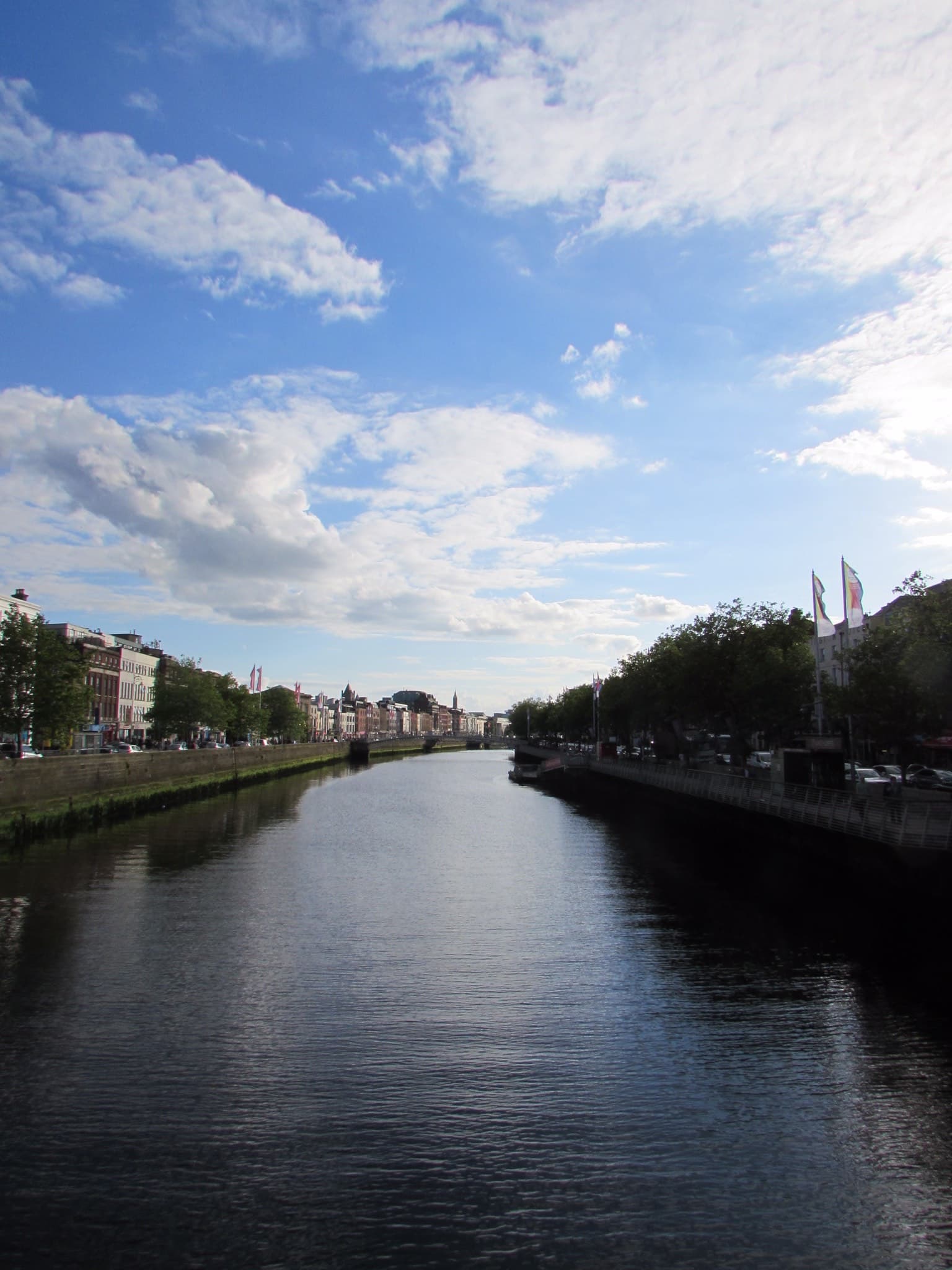 A river way with trees and architecture lining the pathway for boats.