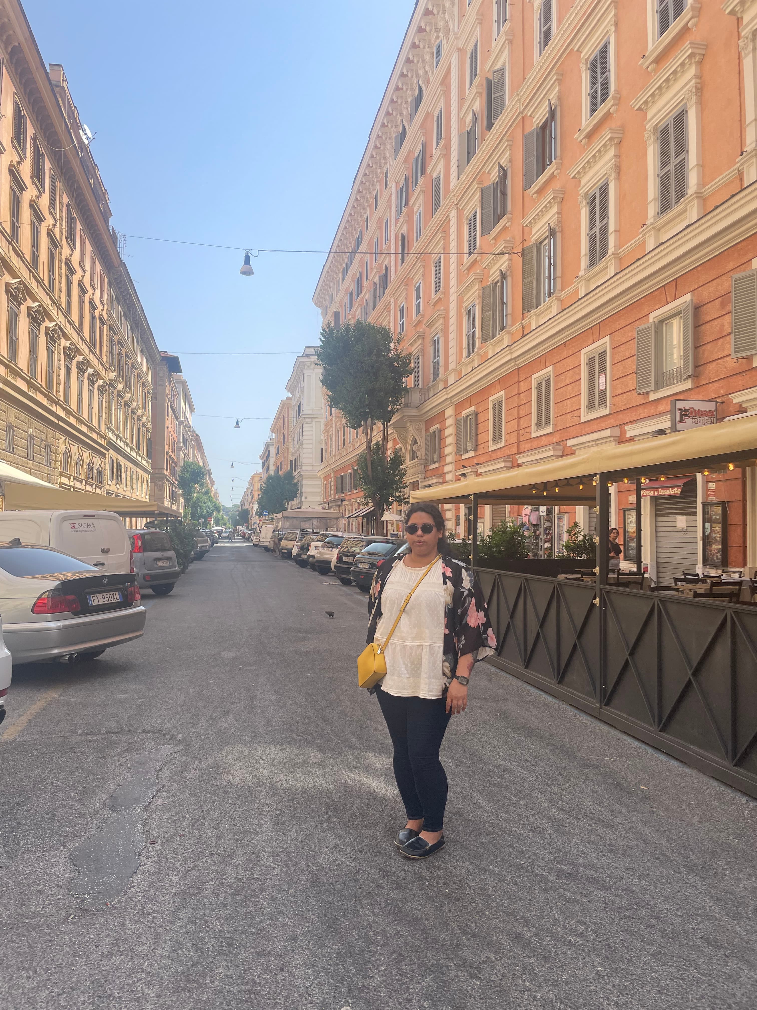 Michelle standing in a street in front of a restaurant between two buildings