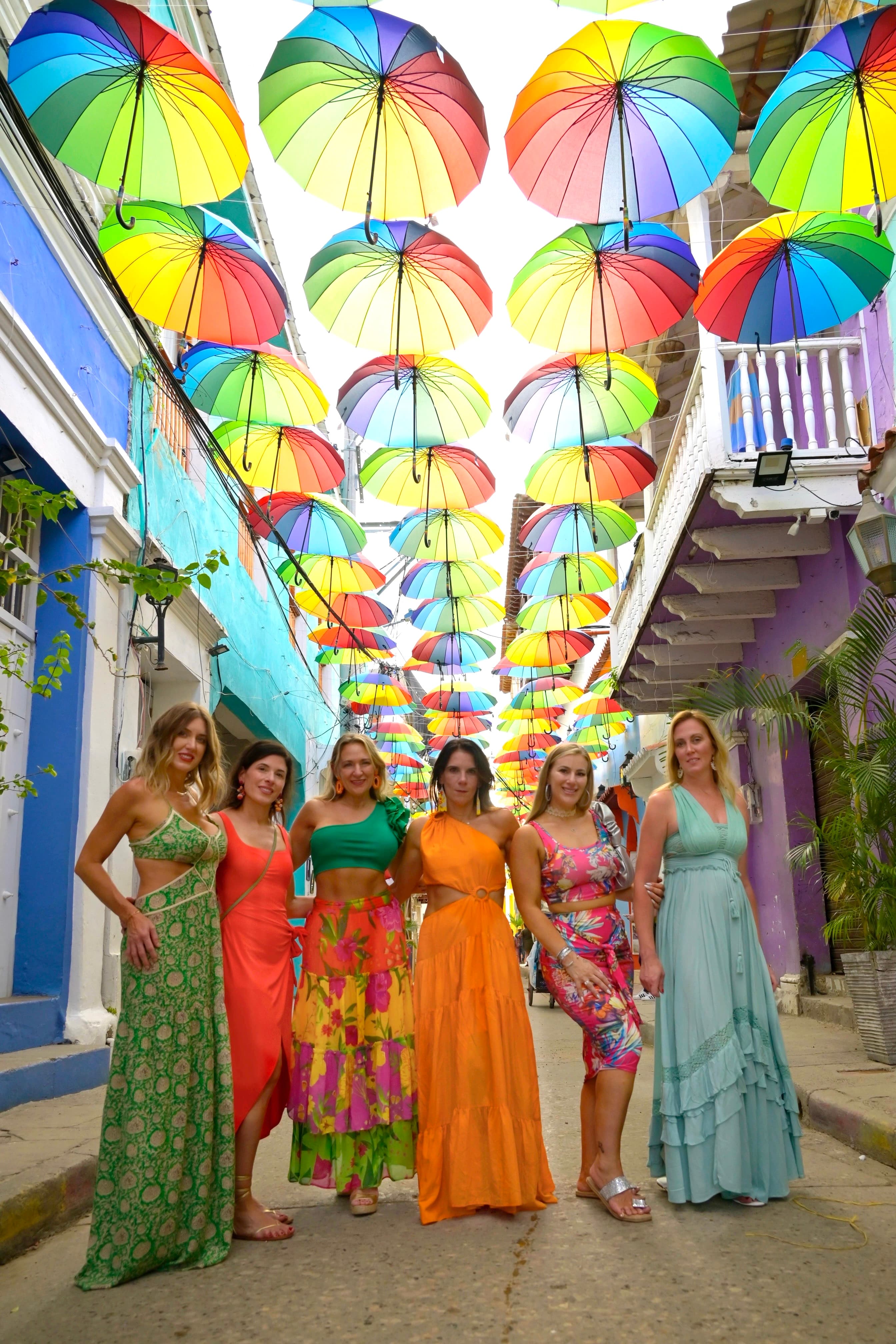 Ladies all dressed up for a photo with colorful umbrellas lining the street