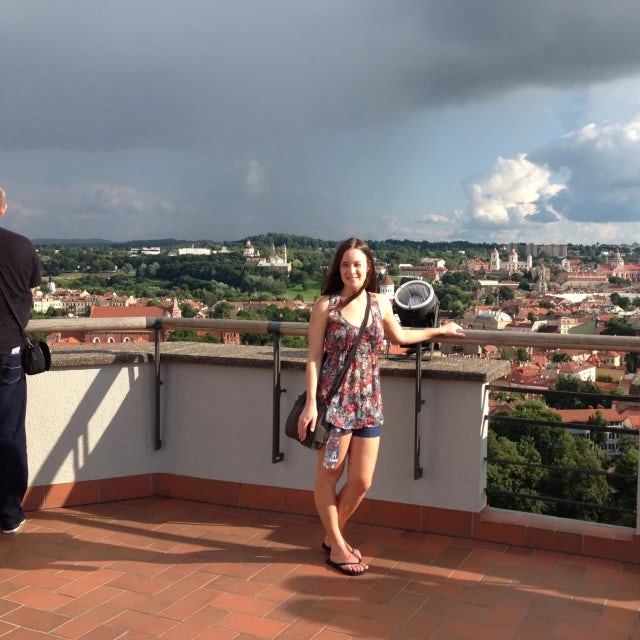 Travel Advisor Jenna Marcinkevicius stands on a roof lookout over a a city with a storm cloud approaching