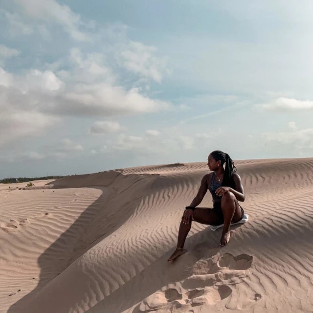 Fora travel agent Erin Brundage sitting on a sand dune