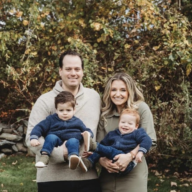Melissa Schwartz smiling with her husband, each holding two young boys in their arms