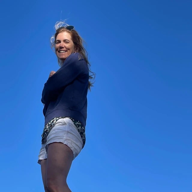 woman wearing black shirt and jean shorts with blue skies