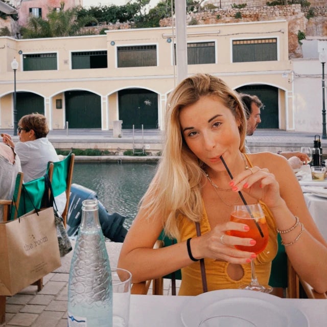 Travel Advisor Julia Lescarbeau along a canal drinking a beverage while sitting at a table.