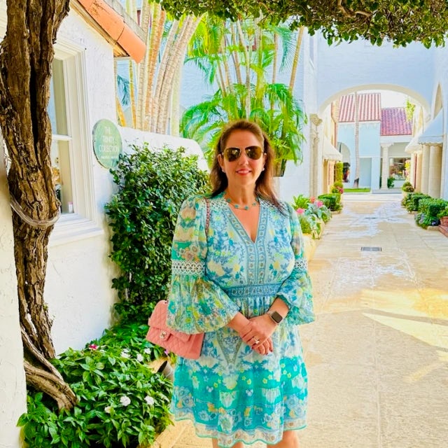 Travel Advisor Lindsay Burkhead in a blue floral dress in front of a tree.